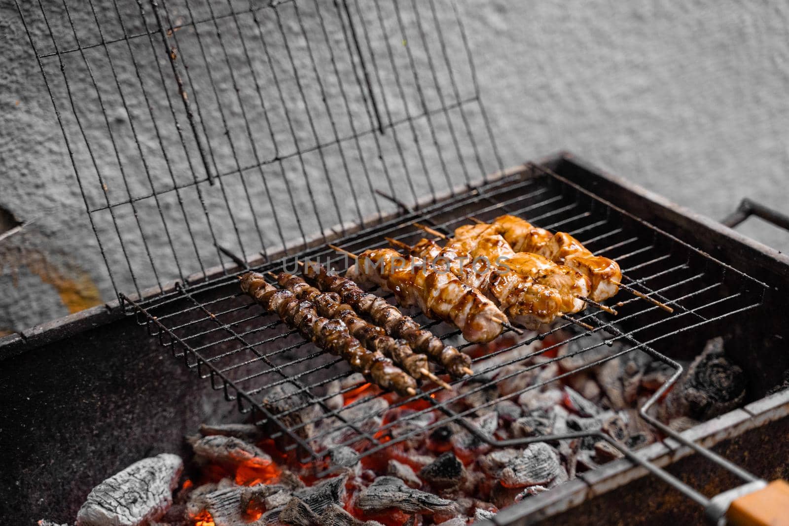 Grilled meat on wooden skewers on metal grill on charcoal. Cooking chicken, hearts. by Rabizo