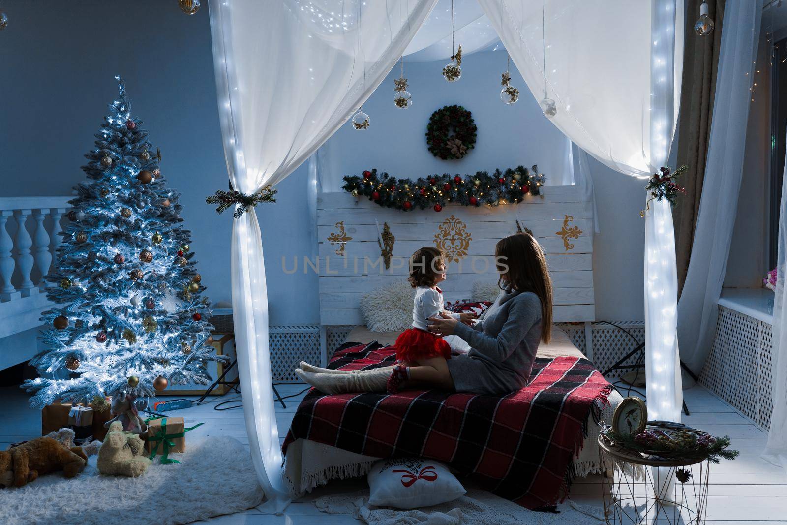 Mother and daughter preparing for christmas celebration. Having fun with family near new year tree. Pregnant woman with daughter