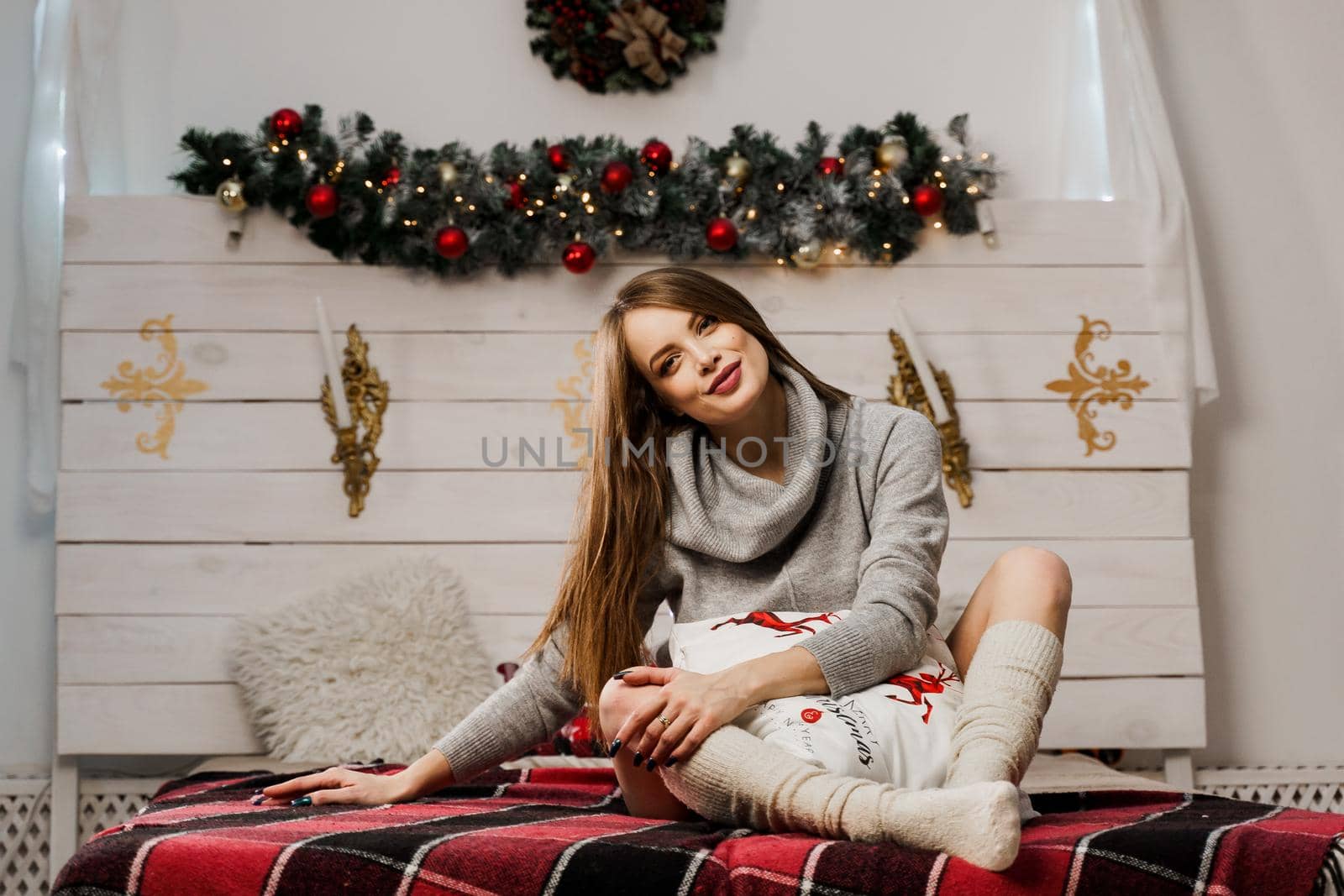 Young woman smiling in new year decoration. Christmas celebration. Attractive girl weared in warm woolen sweater and socks.