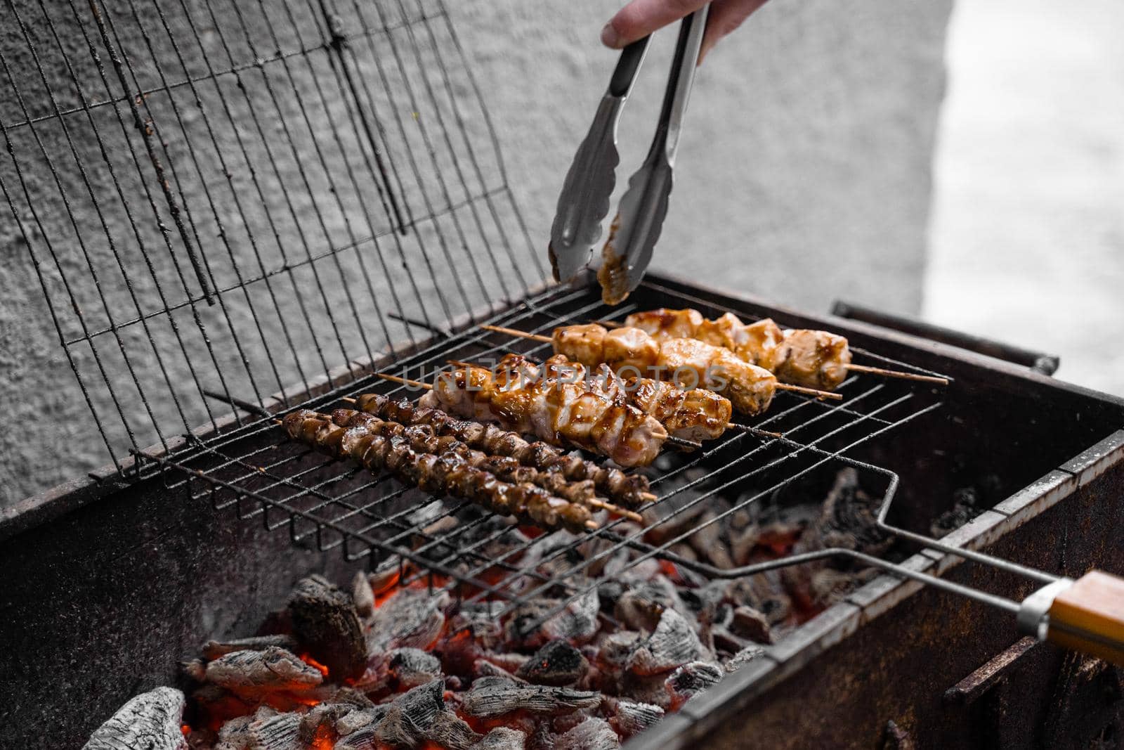 Grilled meat on wooden skewers on metal grill on charcoal. Cooking chicken, hearts. by Rabizo