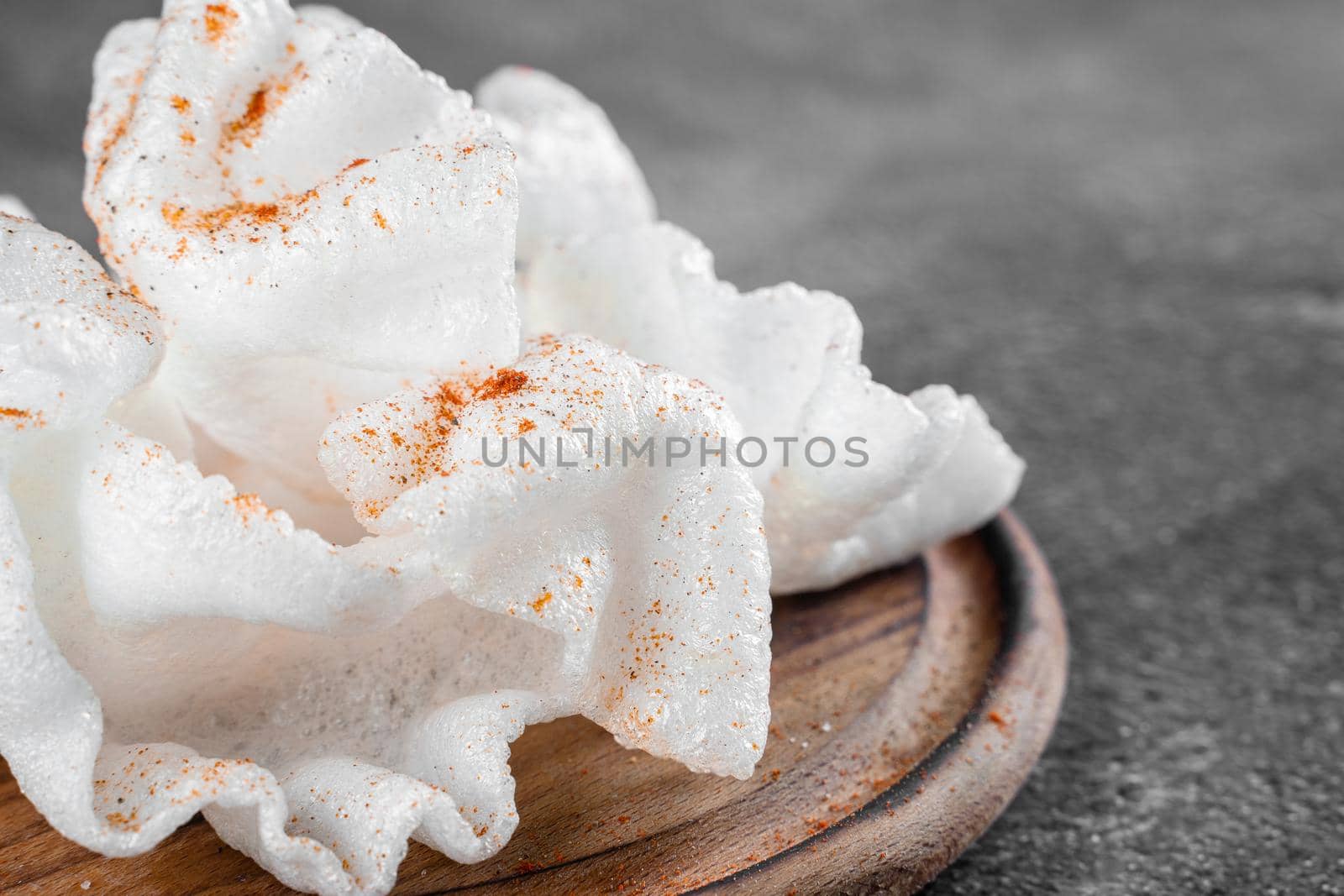 Rice paper chips fried in oil. Rice chips on a wooden board on gray background. by Rabizo