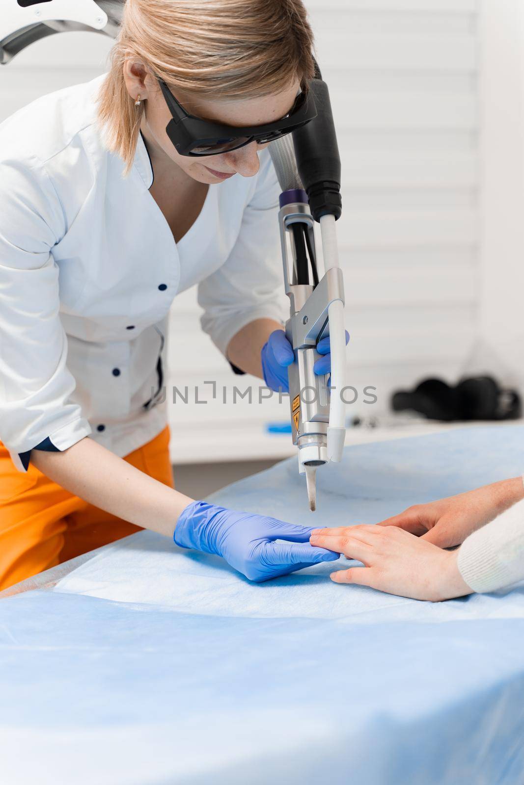 Laser treatment of onychomycosis. fungal infection on the hands of a young girl in medical clinic.