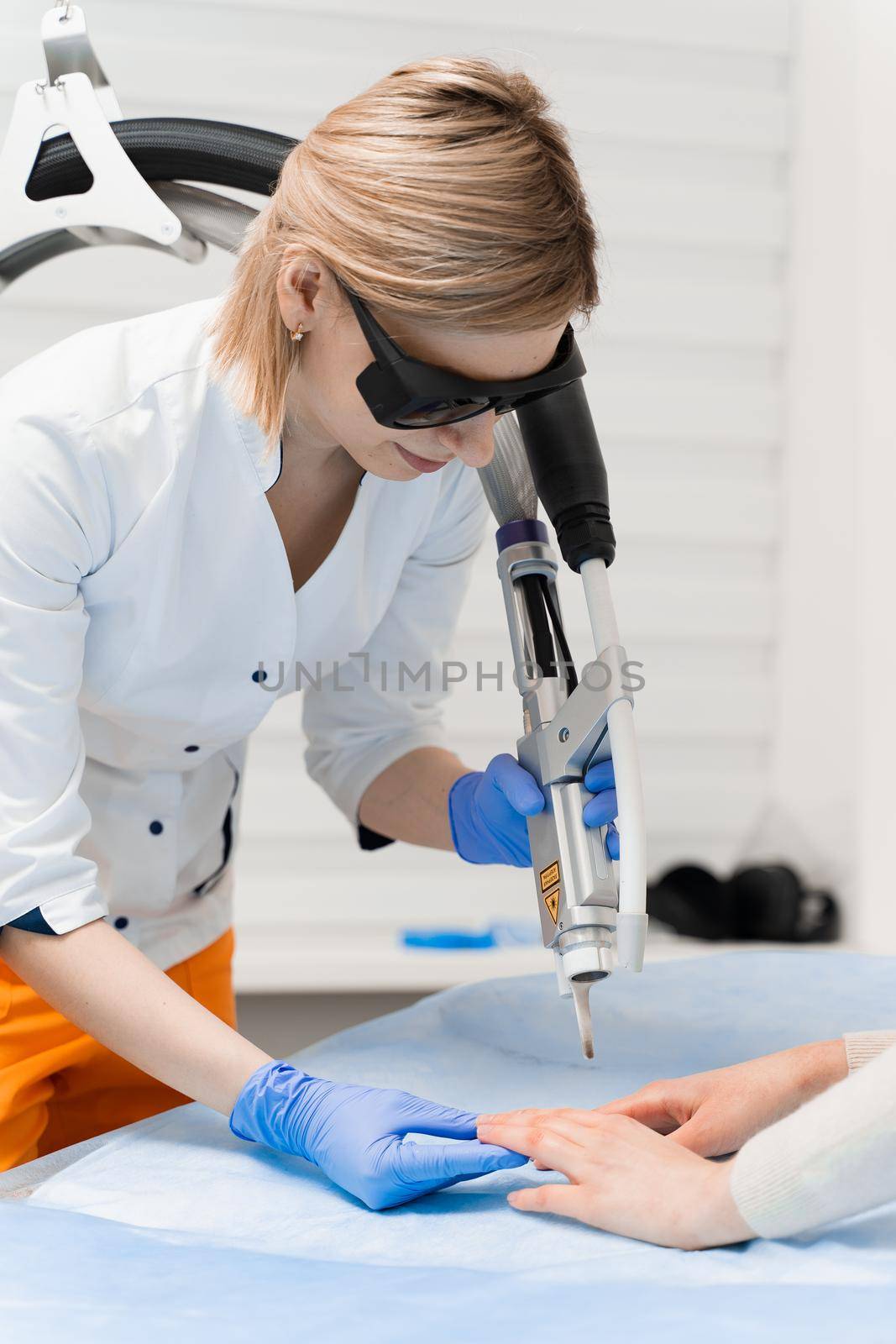 Laser treatment of onychomycosis. fungal infection on the hands of a young girl in medical clinic.