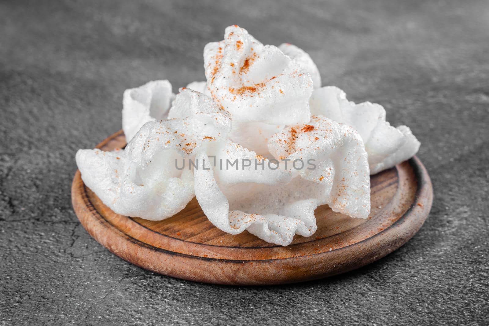 Rice paper chips fried in oil. Rice chips on a wooden board on gray background