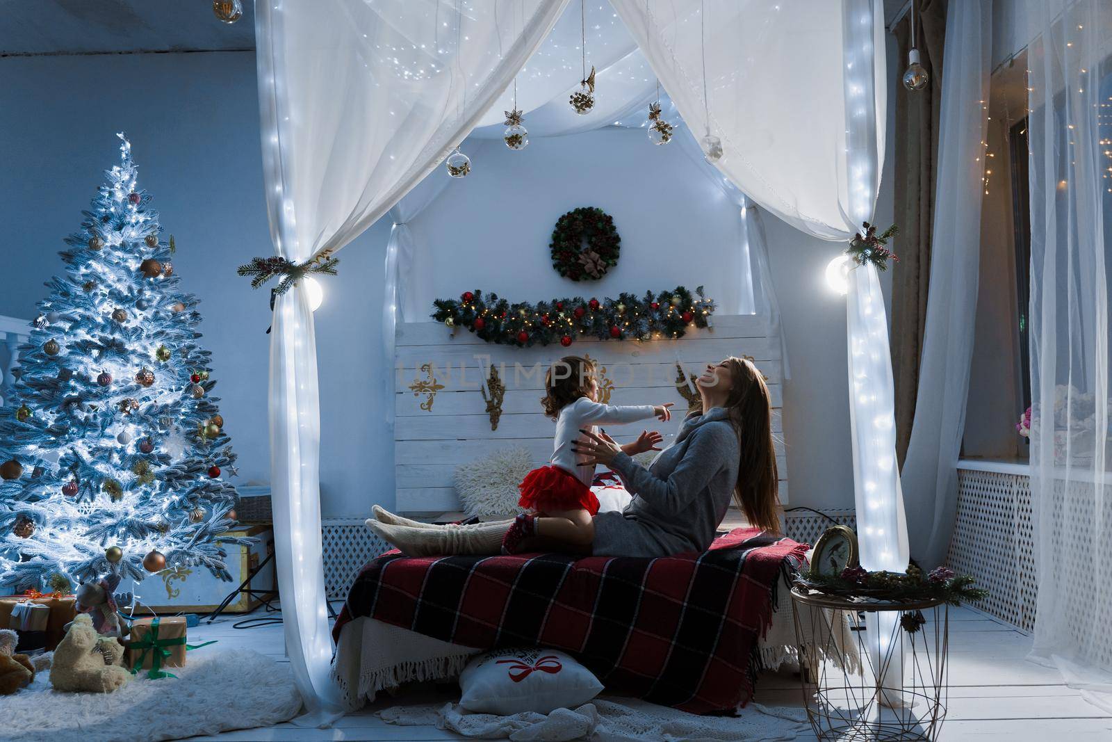 Mother and daughter preparing for christmas celebration. Having fun with family near new year tree. Pregnant woman with daughter