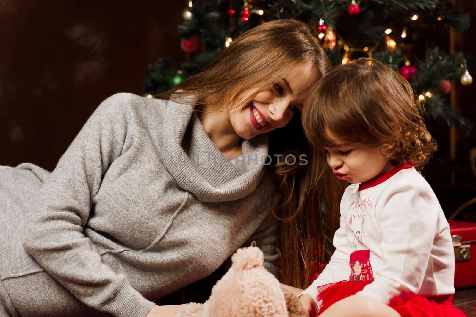 Mother and daughter preparing for christmas celebration. Having fun with family near new year tree. Pregnant woman with daughter. by Rabizo