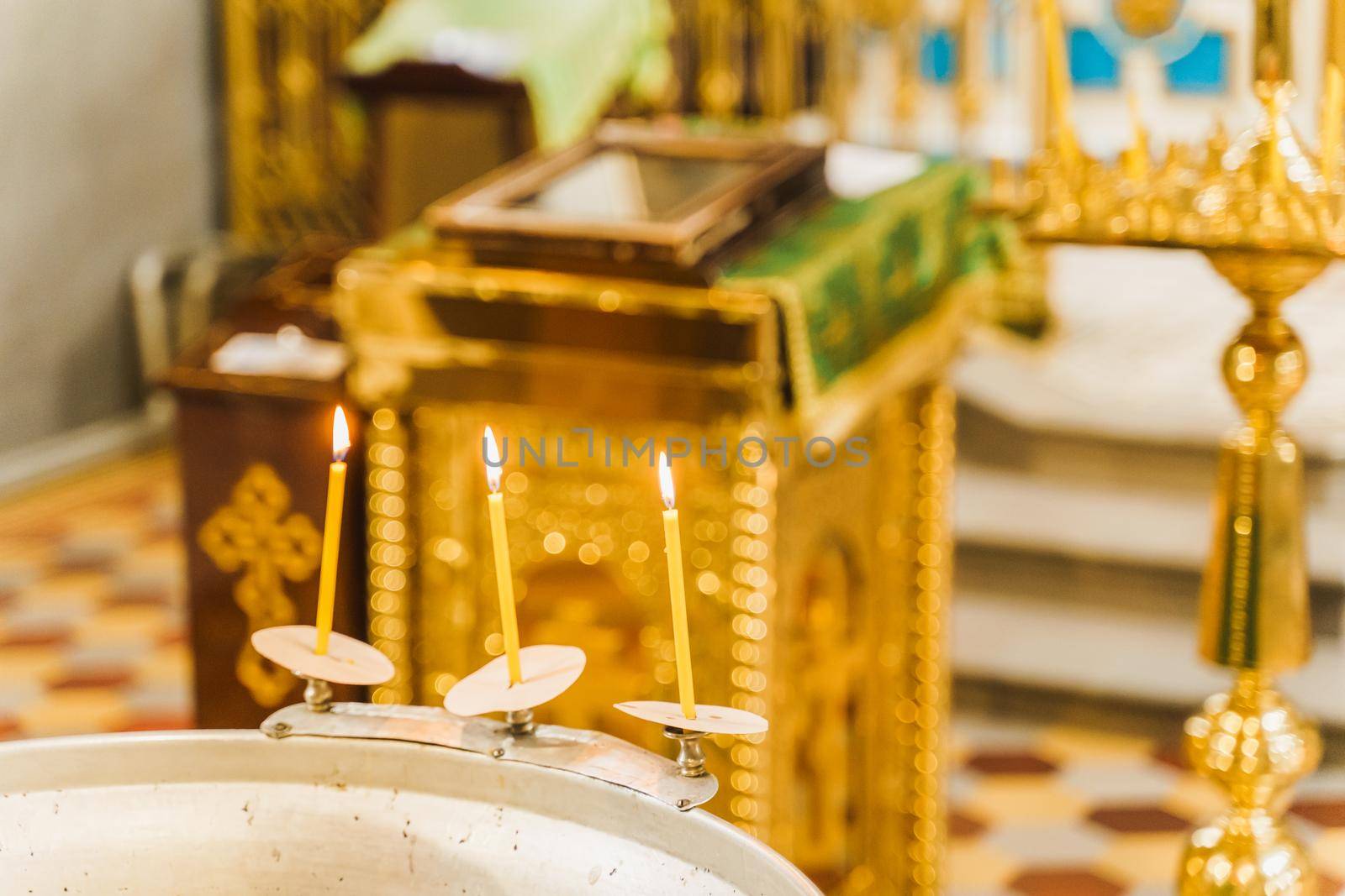 Font and 3 burning candles with water for baby in church for Epiphany. Prepearing for bathing for child in a baptistery