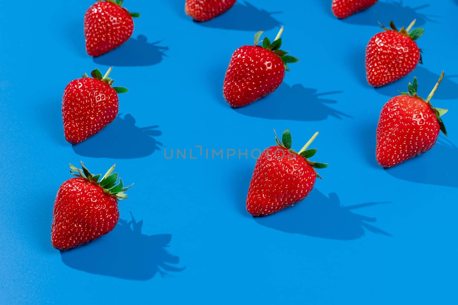 Strawberry ripe fruit on blue background. Harvest of fresh red berry by Rabizo