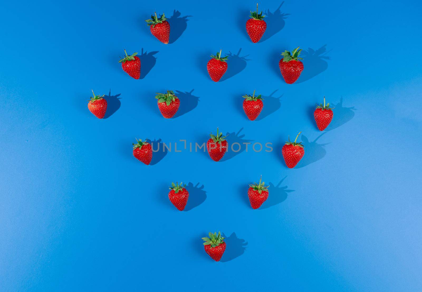 Red strawberries on blue background. Ripe tasty berry. by Rabizo