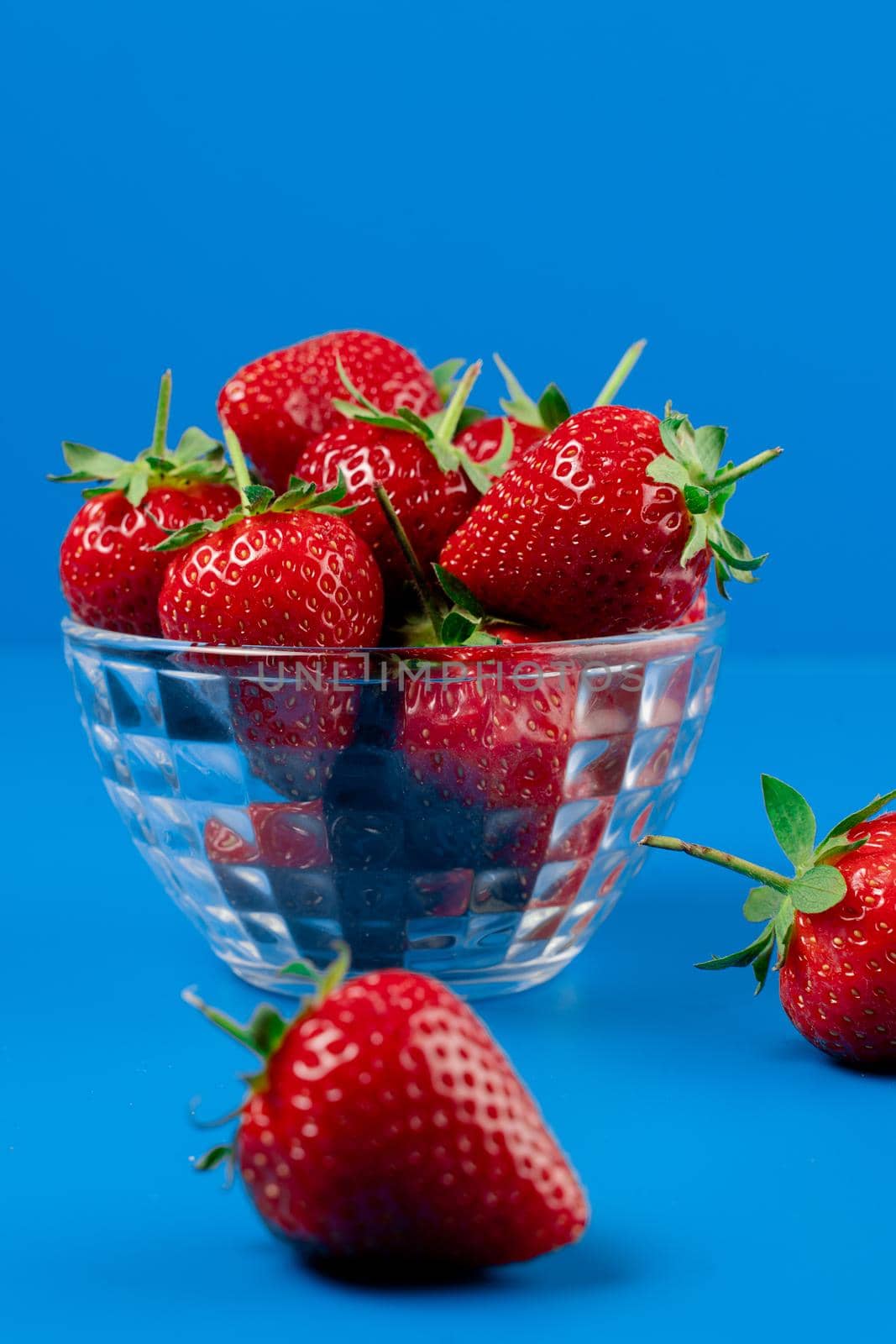 Bunch of strawberry in bowl on blue background. Yummy summer fruit. by Rabizo