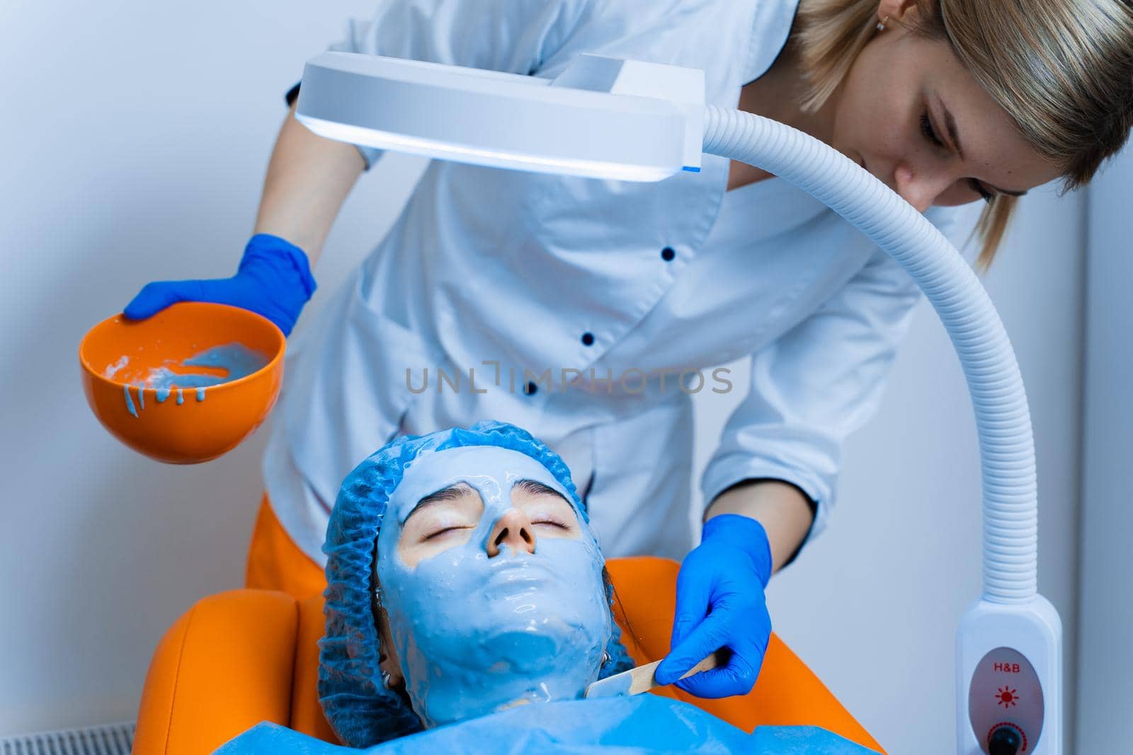 Alginate moisturizing mask for face and skin of young girl. Spa procedure for rejuvenation. beautician smears blue mask. Dermatology in medical clinic