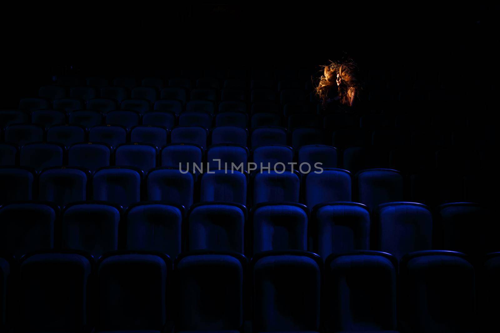 The girl who plays the role of a Ghost or spirit in the theater is sitting between the rows of chairs by deandy