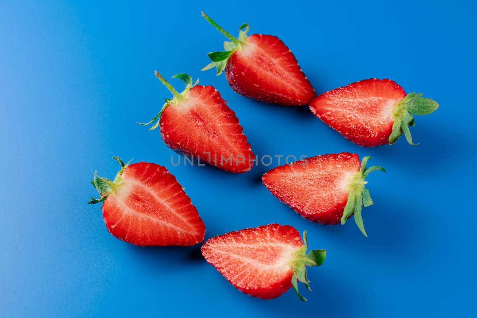 Sliced strawberry slices on blue background. by Rabizo