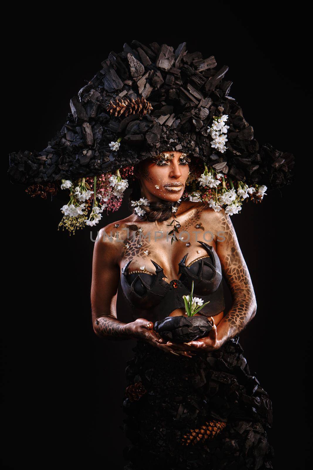 Portrait of a model in a headdress and dress made of coal. Bright makeup and body art by deandy