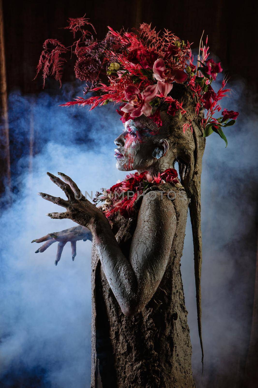 A girl smeared with clay. The model has a headdress made of flowers.