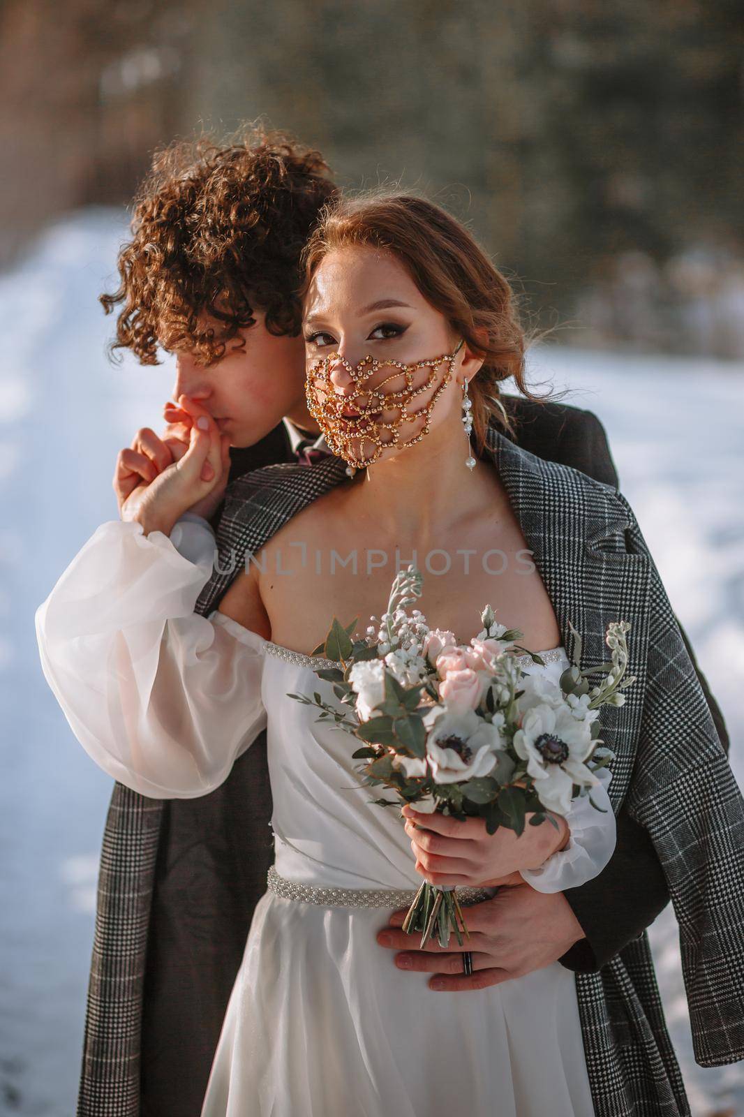 The bride and groom are standing in a snow-covered forest.