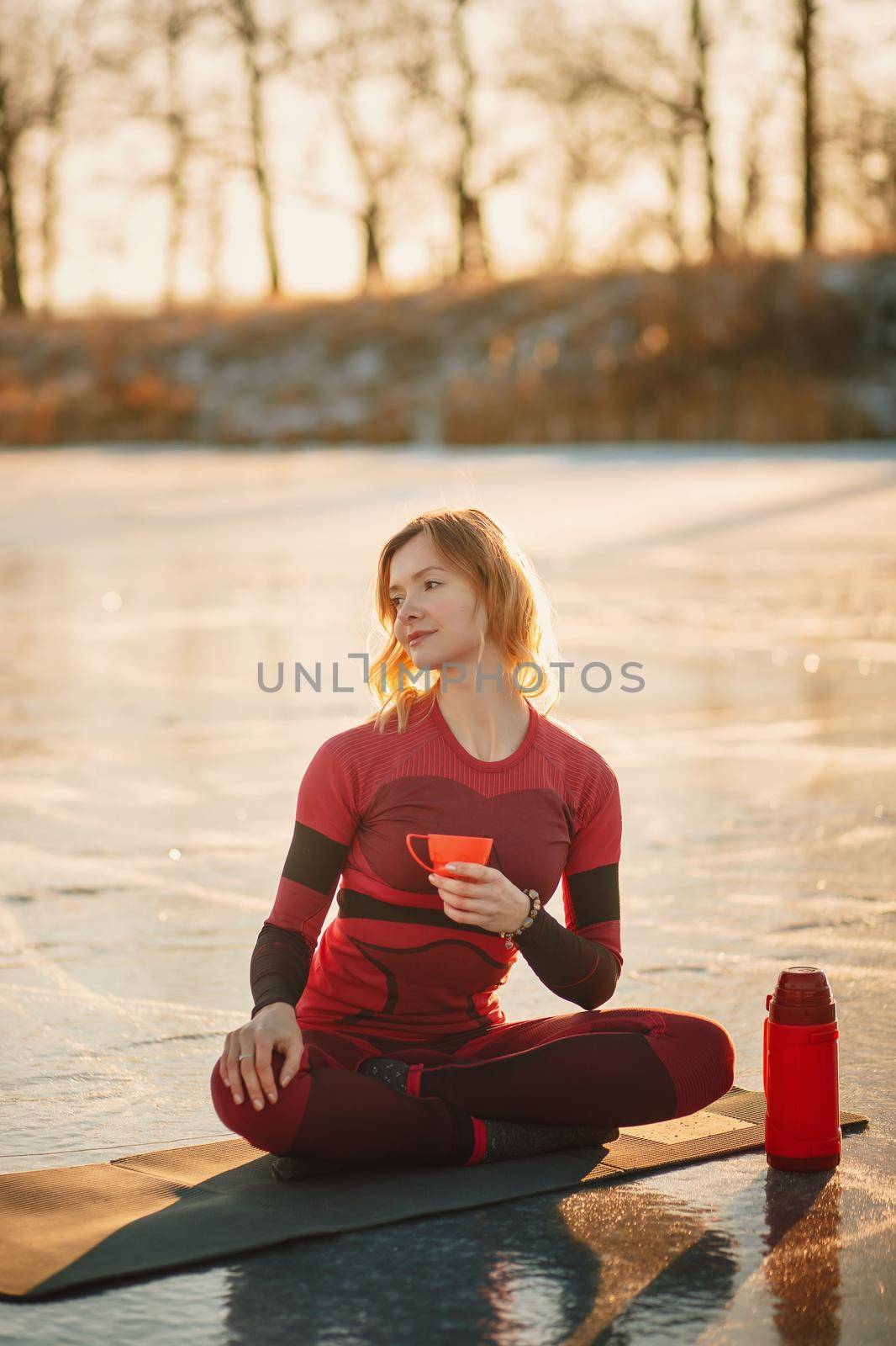 A girl does yoga in winter on the ice of the lake