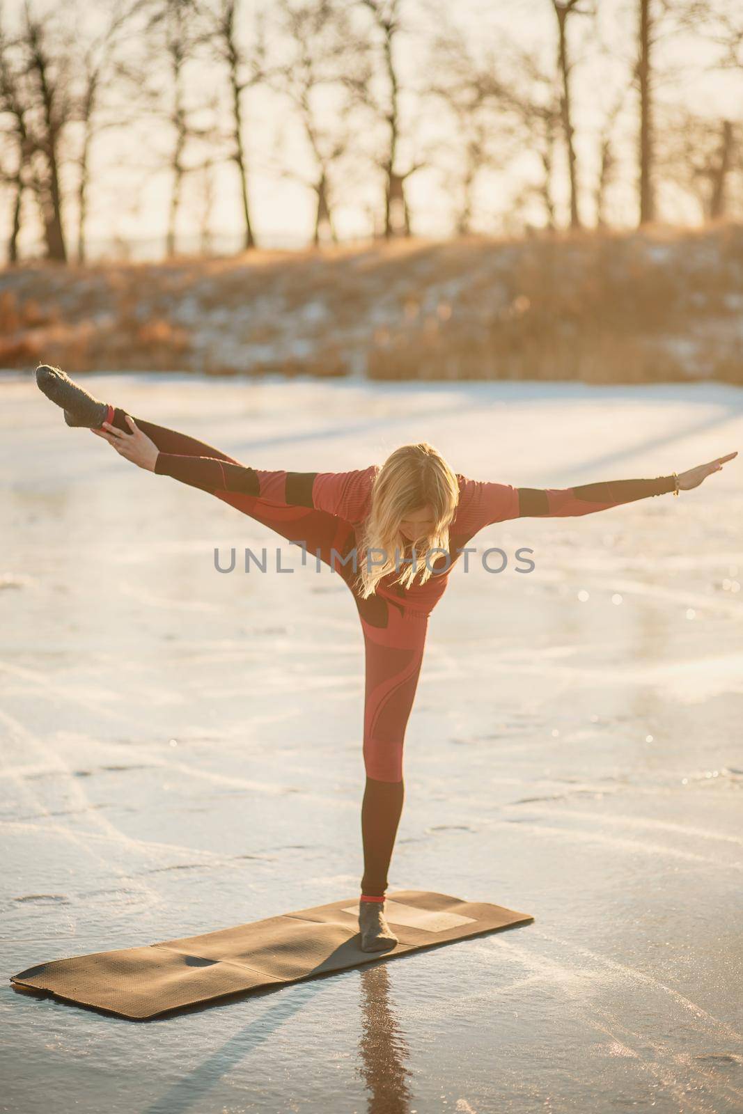 A girl does yoga in winter on the ice of the lake