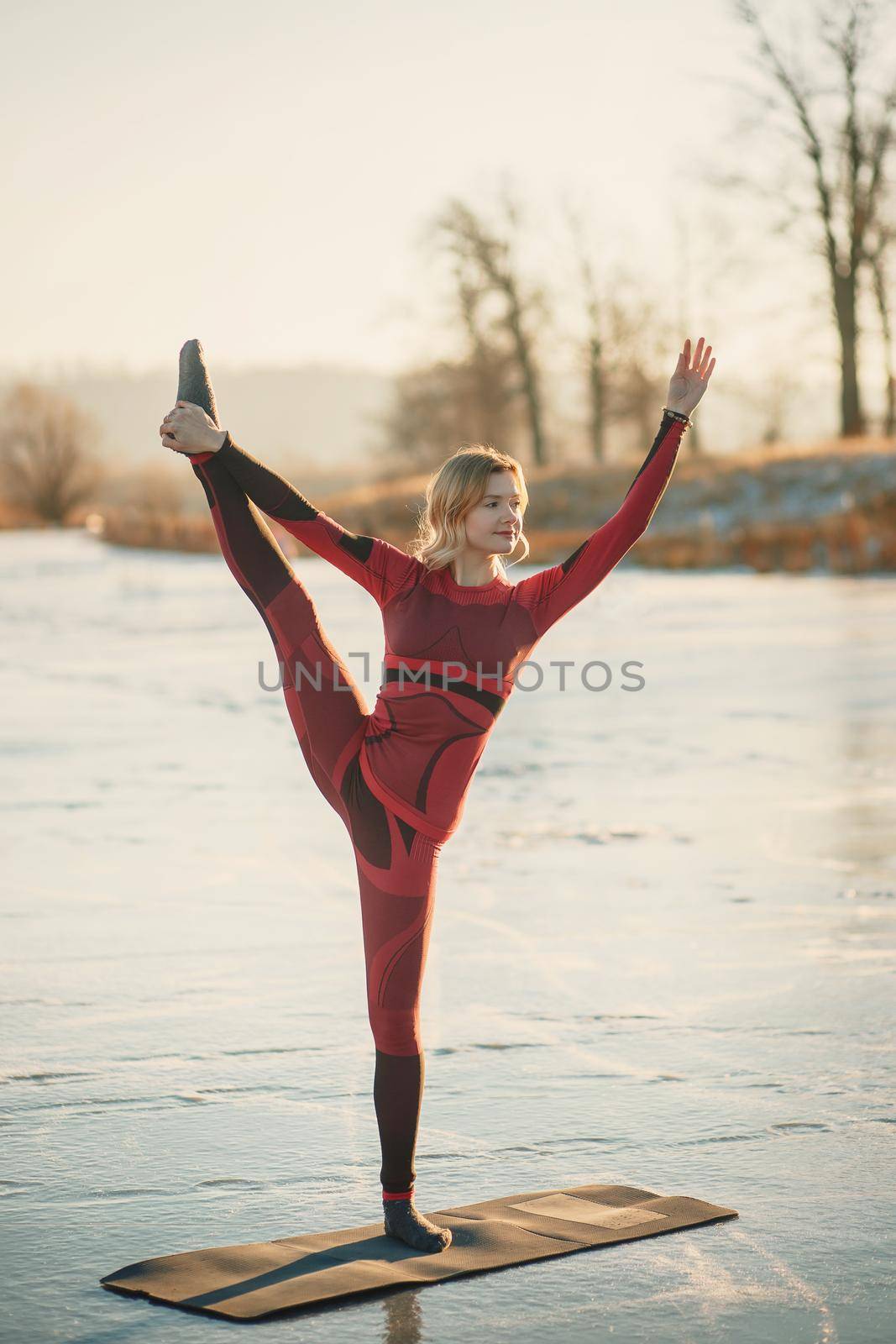 A girl does yoga in winter on the ice of the lake