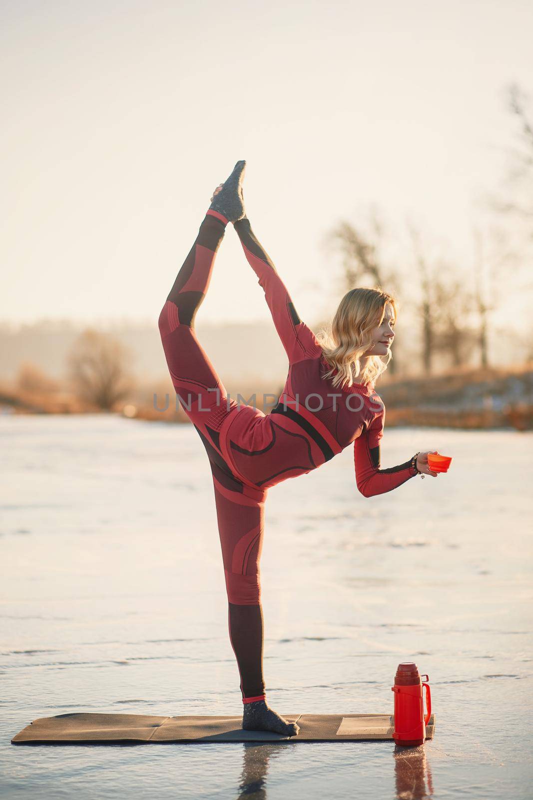 A girl does yoga in winter on the ice of the lake