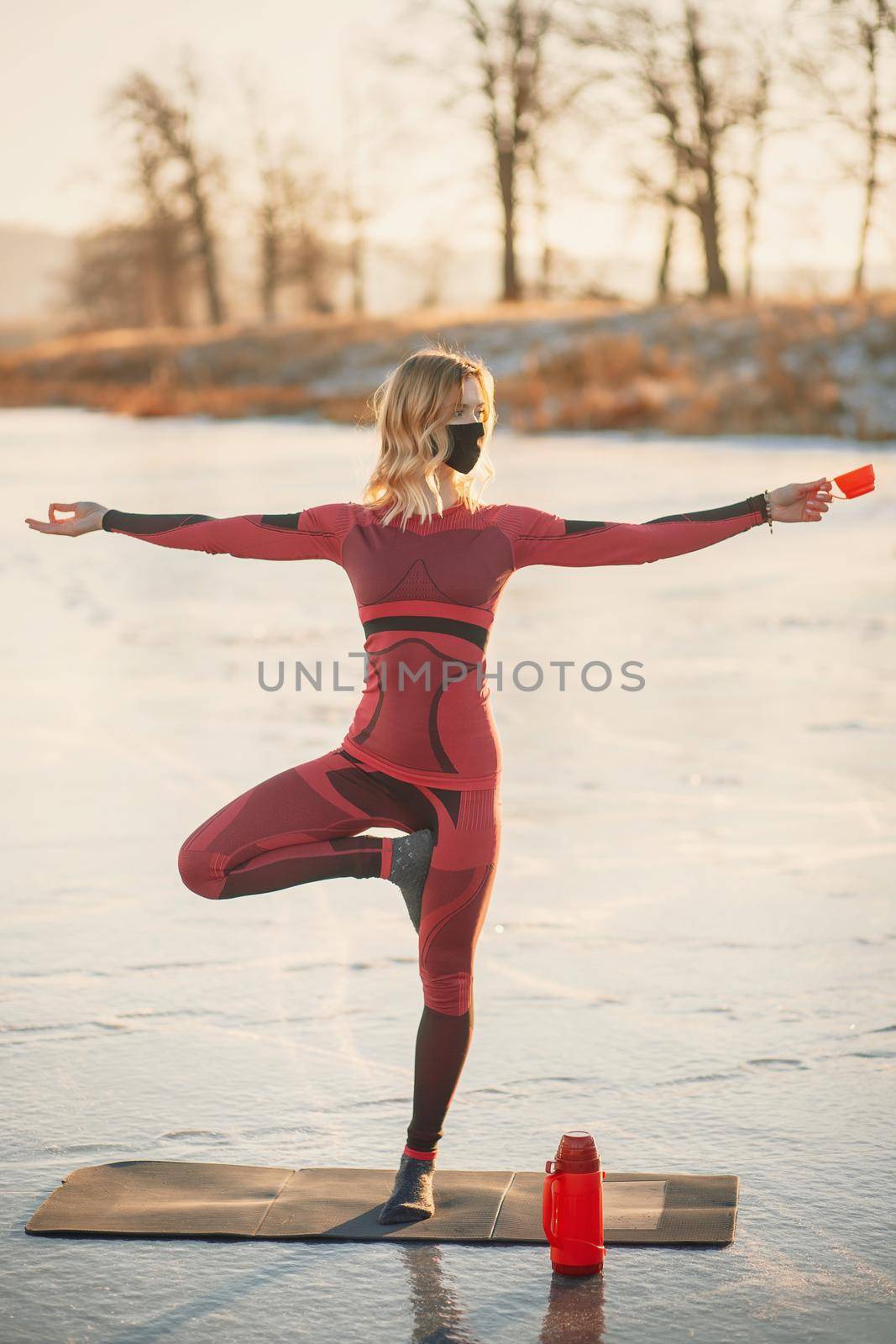A girl does yoga in winter on the ice of the lake