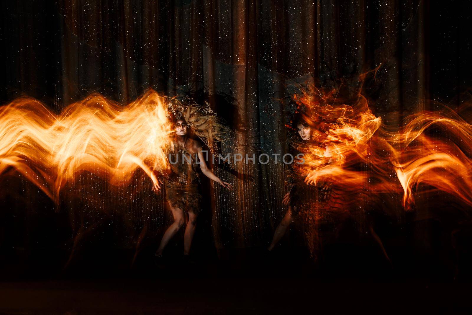 Ghost girls, spirits of the theater, accompanied by a trail of fire, on the stage of the theater.