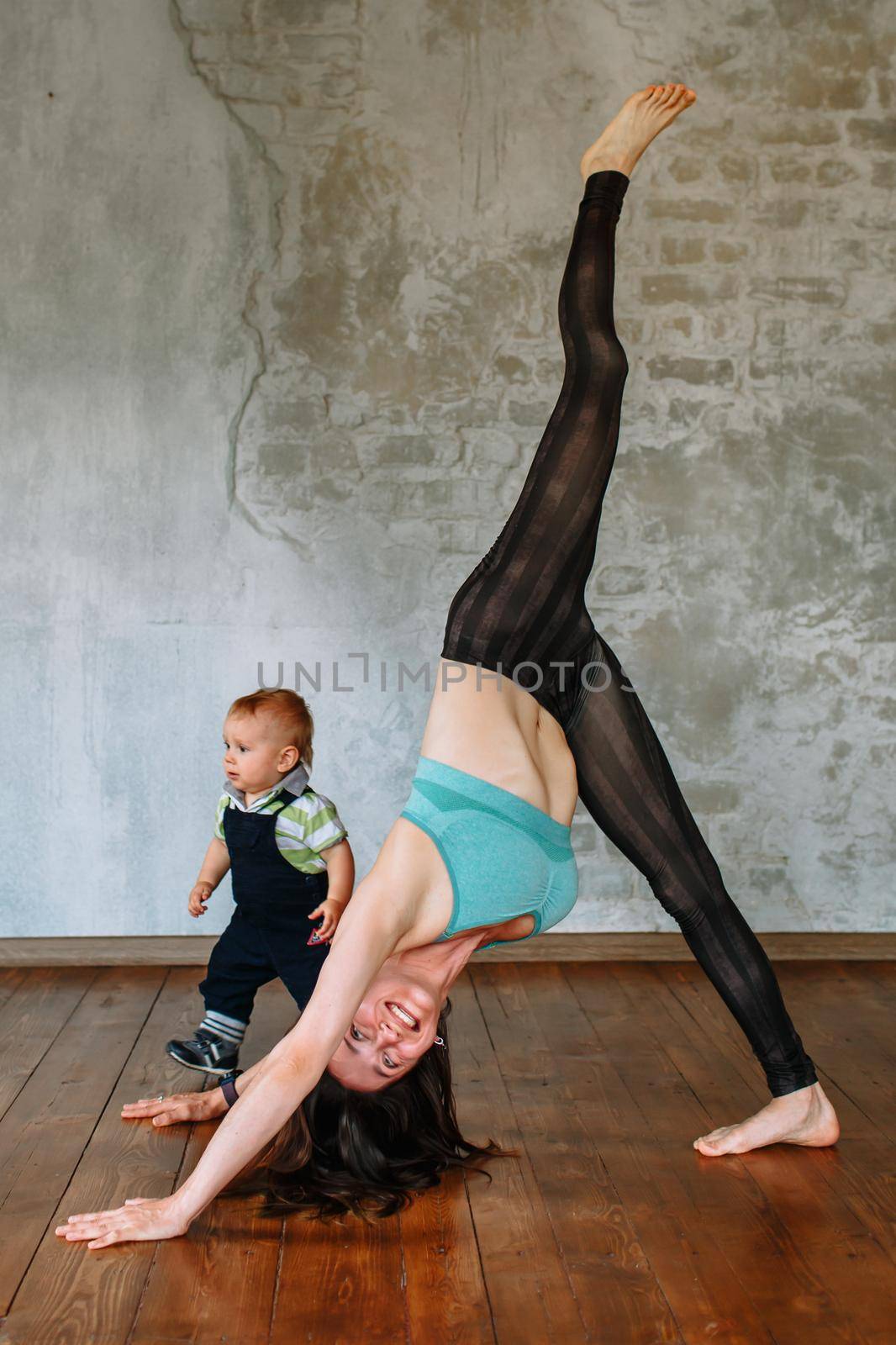 Yoga girl performs an exercise, next to her little son