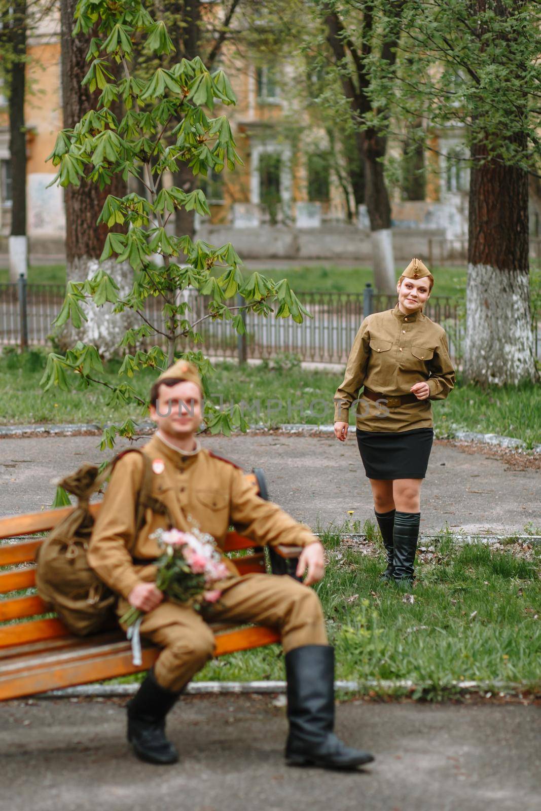 A soldier sitting on a bench waiting, with a bouquet in his hands. A soldier is waiting for a girl