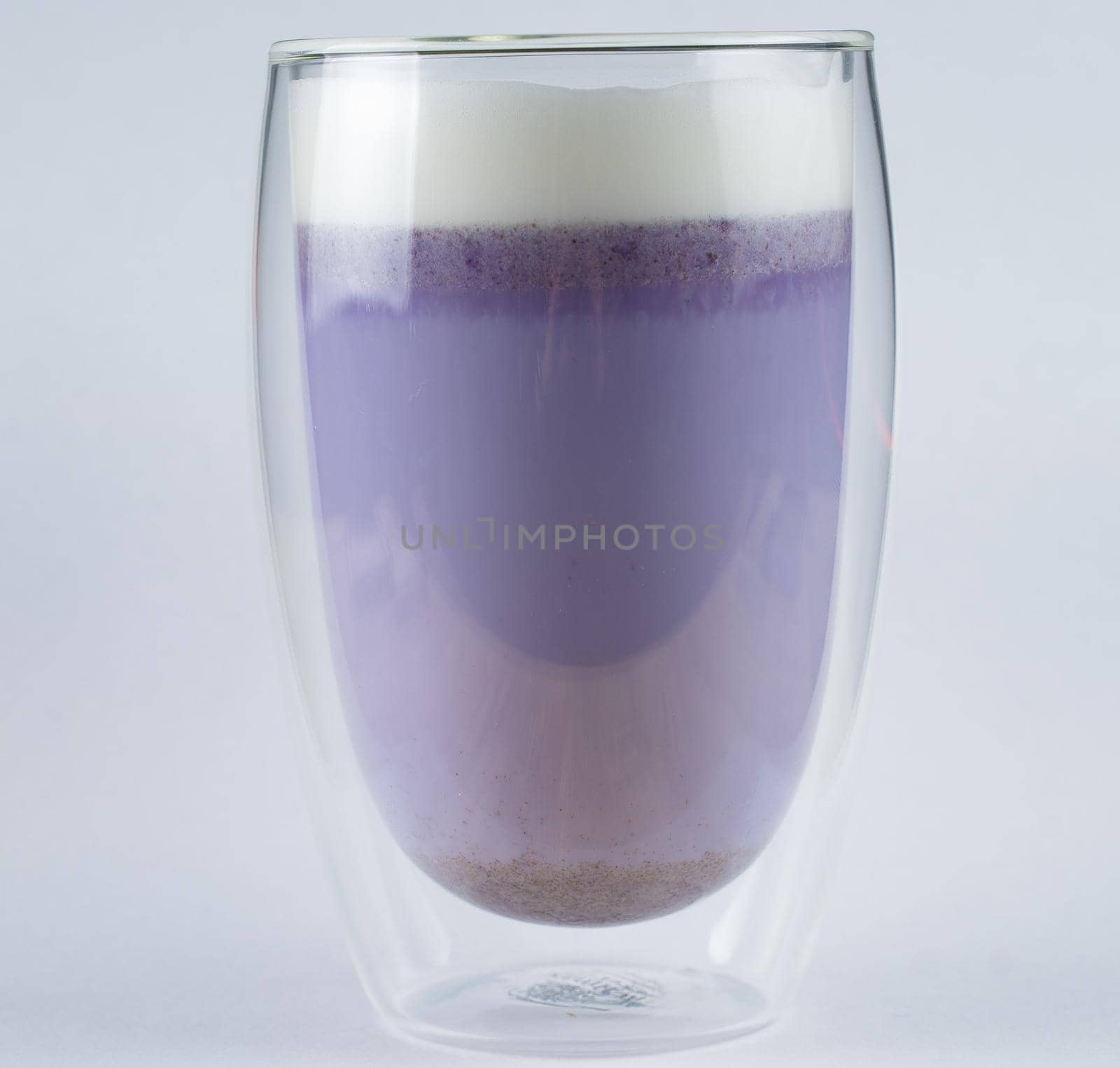 Purple goji matcha on blue background. Matcha cocktail in double glass cup