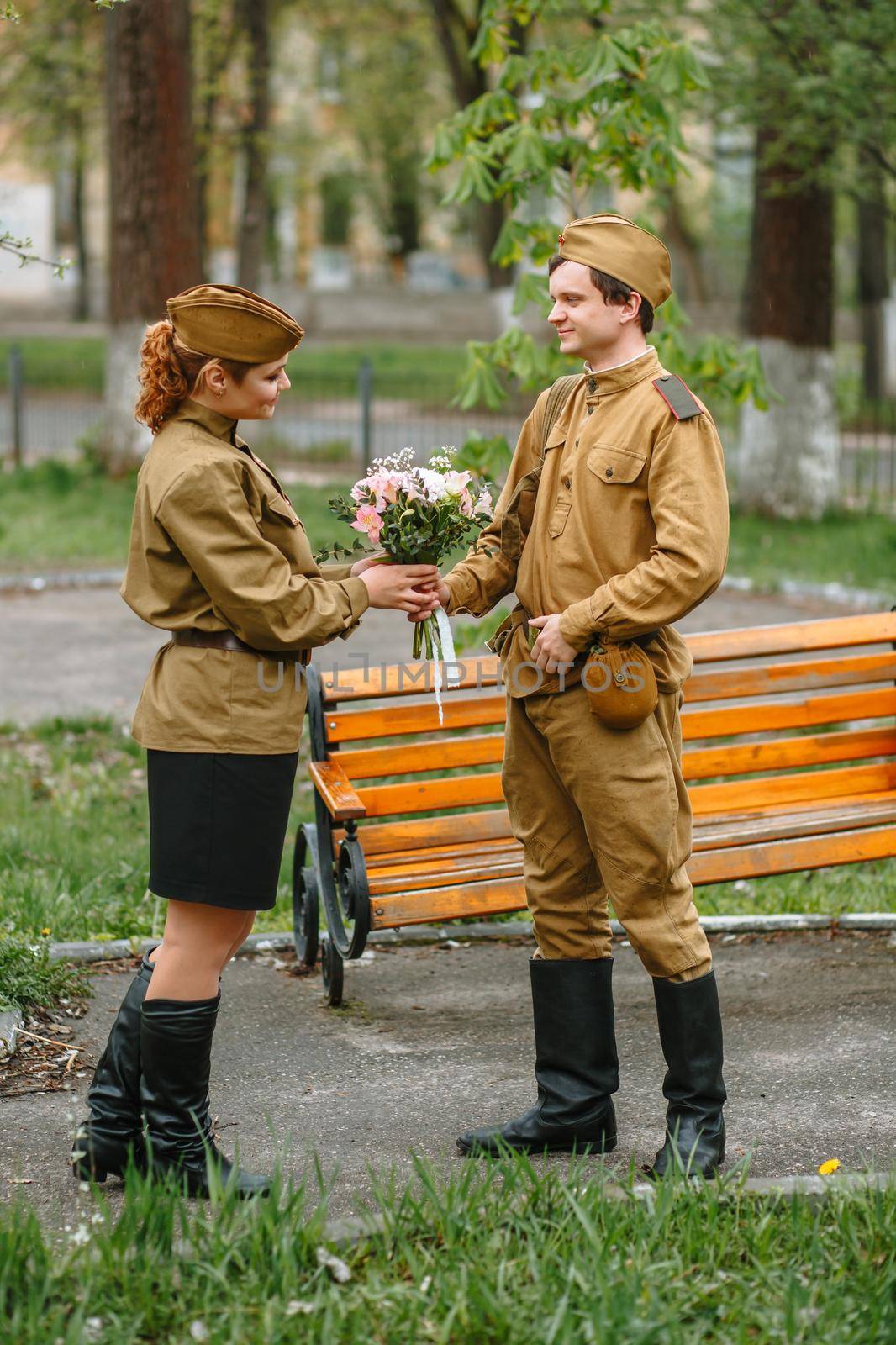 A military girl and a soldier in a Soviet military uniform. Military gives a girl a bouquet
