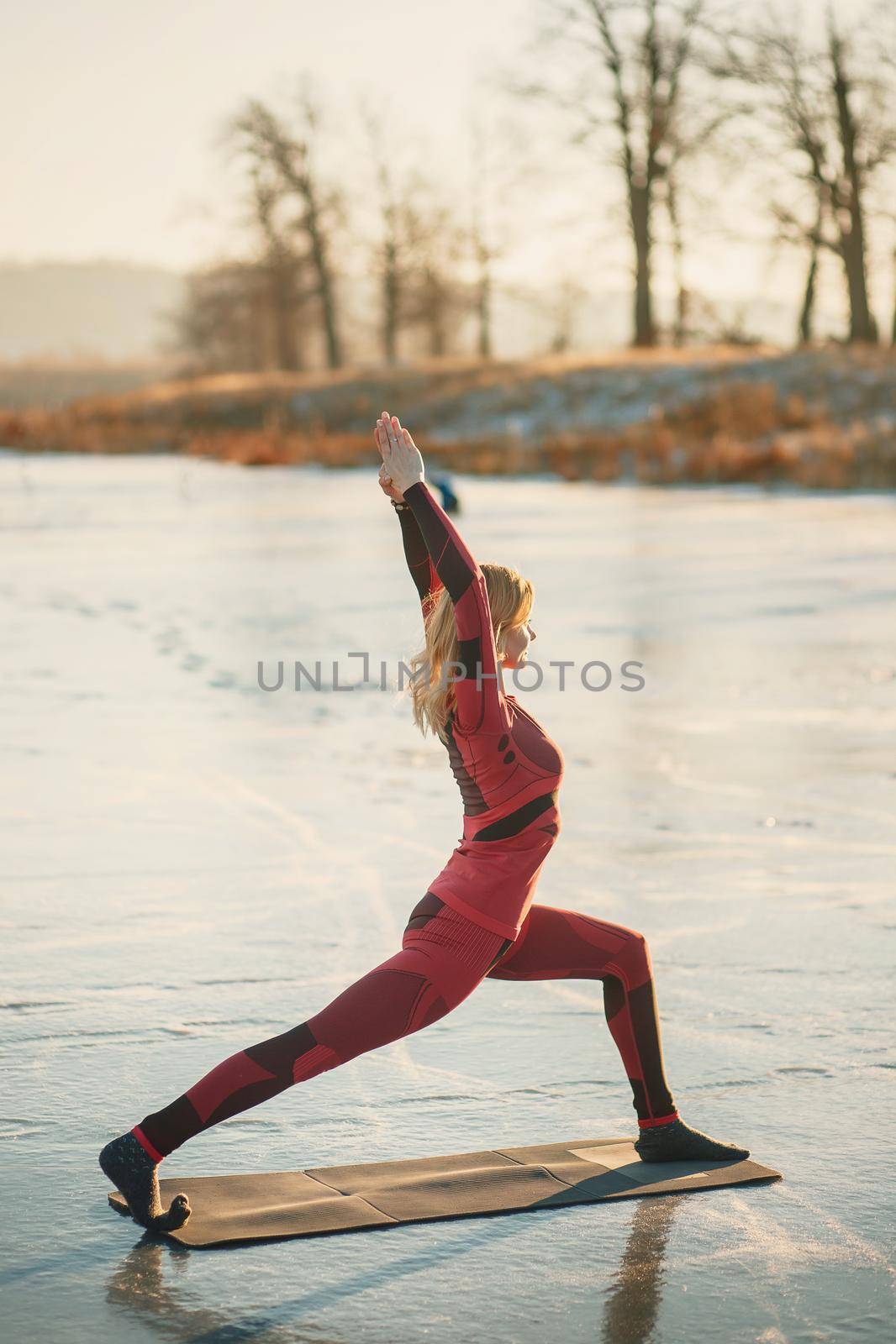 A girl does yoga in winter on the ice of the lake