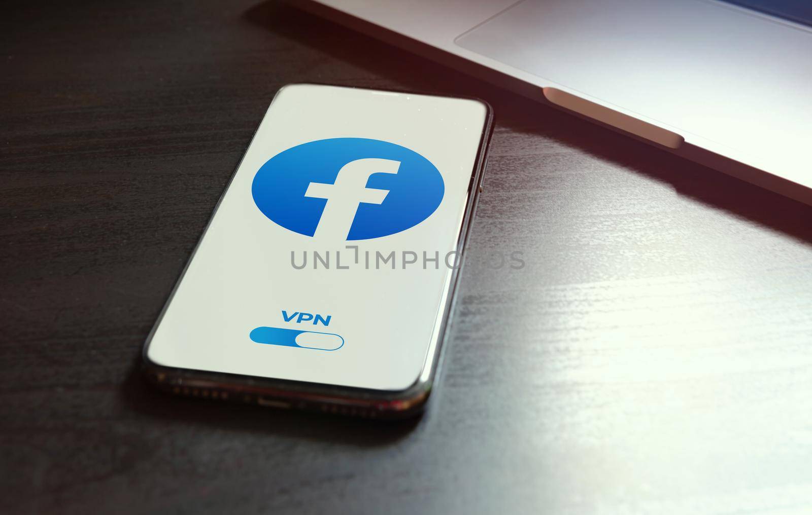 MOSCOW, RUSSIA - MAY 03, 2022: iphone lying on a wooden table, on the screen Facebook social application logo, which starts only after turning on the vpn connection. Government censorship concept by bestforbest