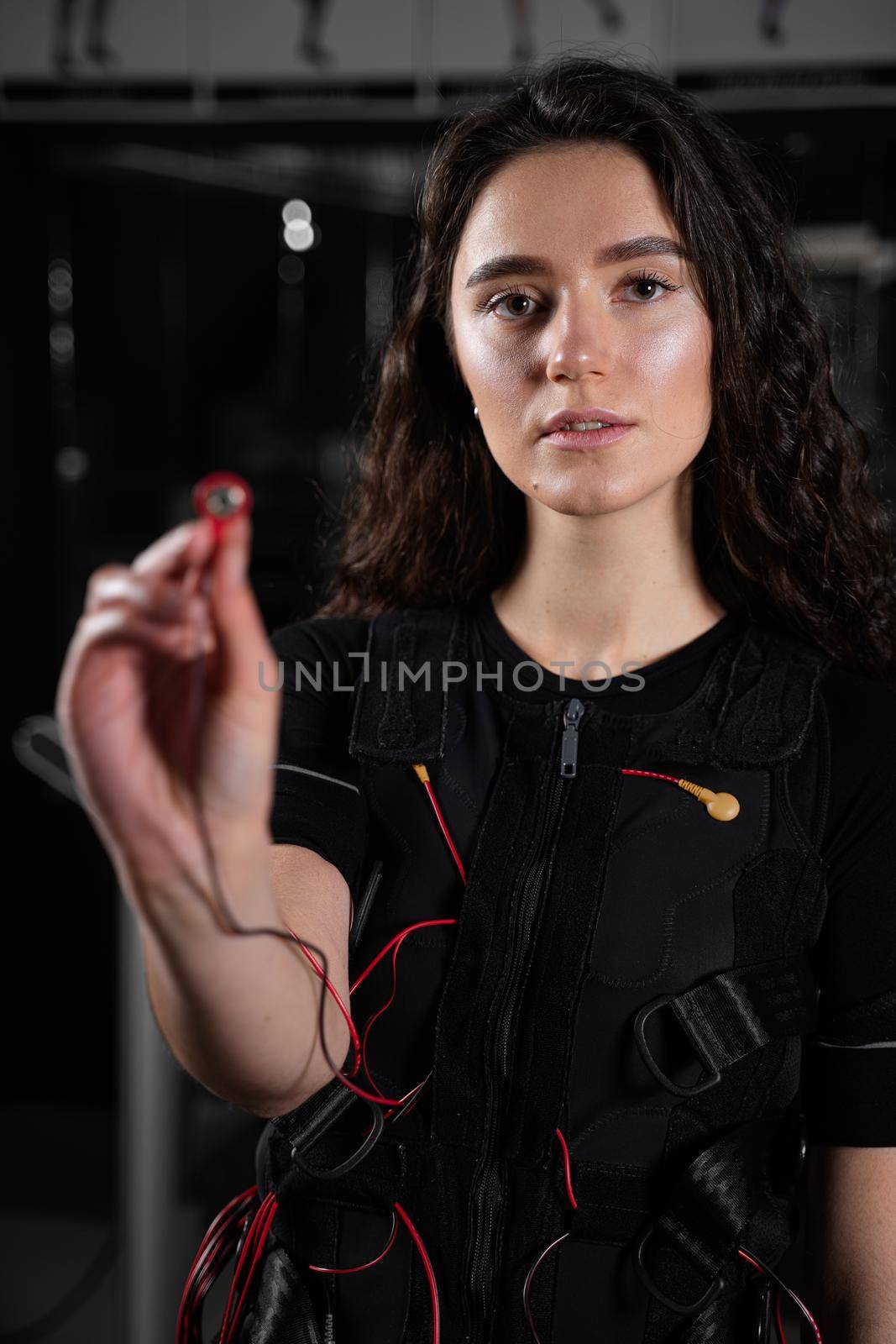 Girl with electronic contactor of EMS suit in gym. Sport training in electrical muscle stimulation suit