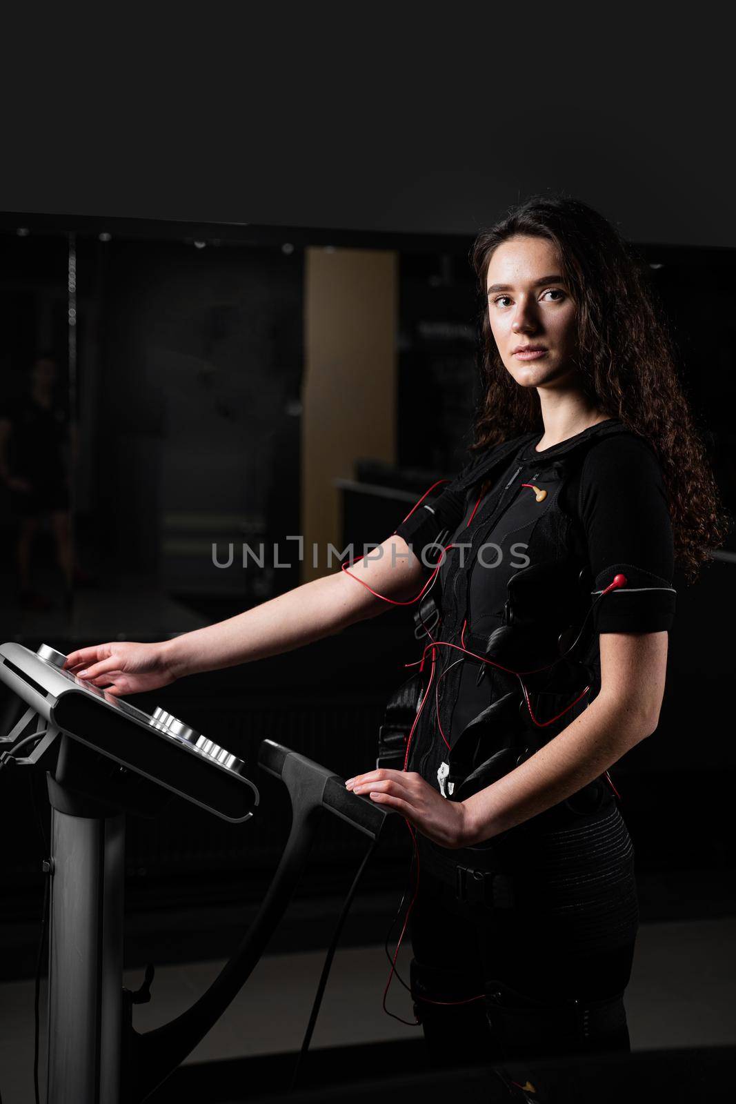 Girl in EMS suit in gym. Sport training in electrical muscle stimulation suit. by Rabizo