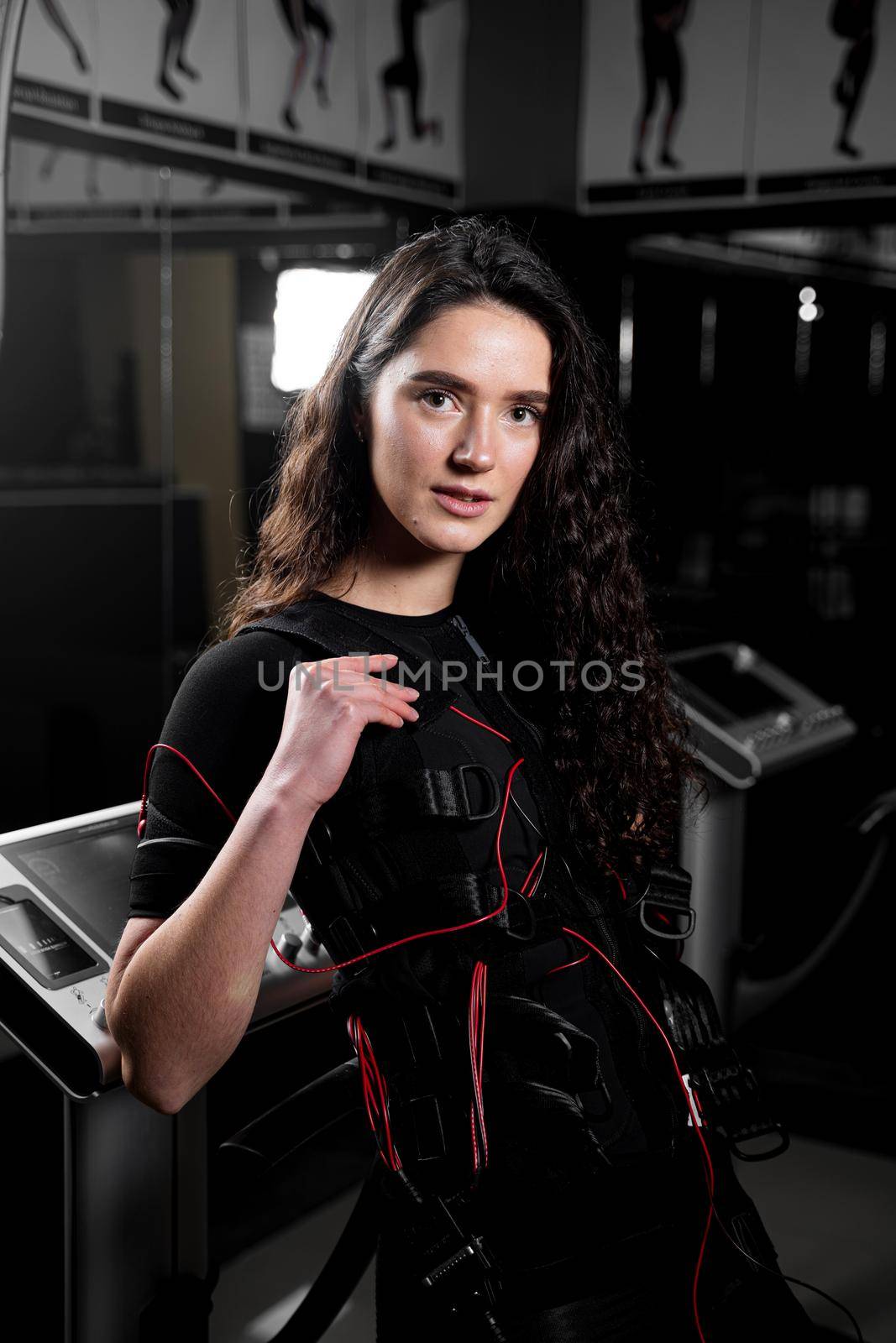 Girl in EMS suit in gym. Sport training in electrical muscle stimulation suit