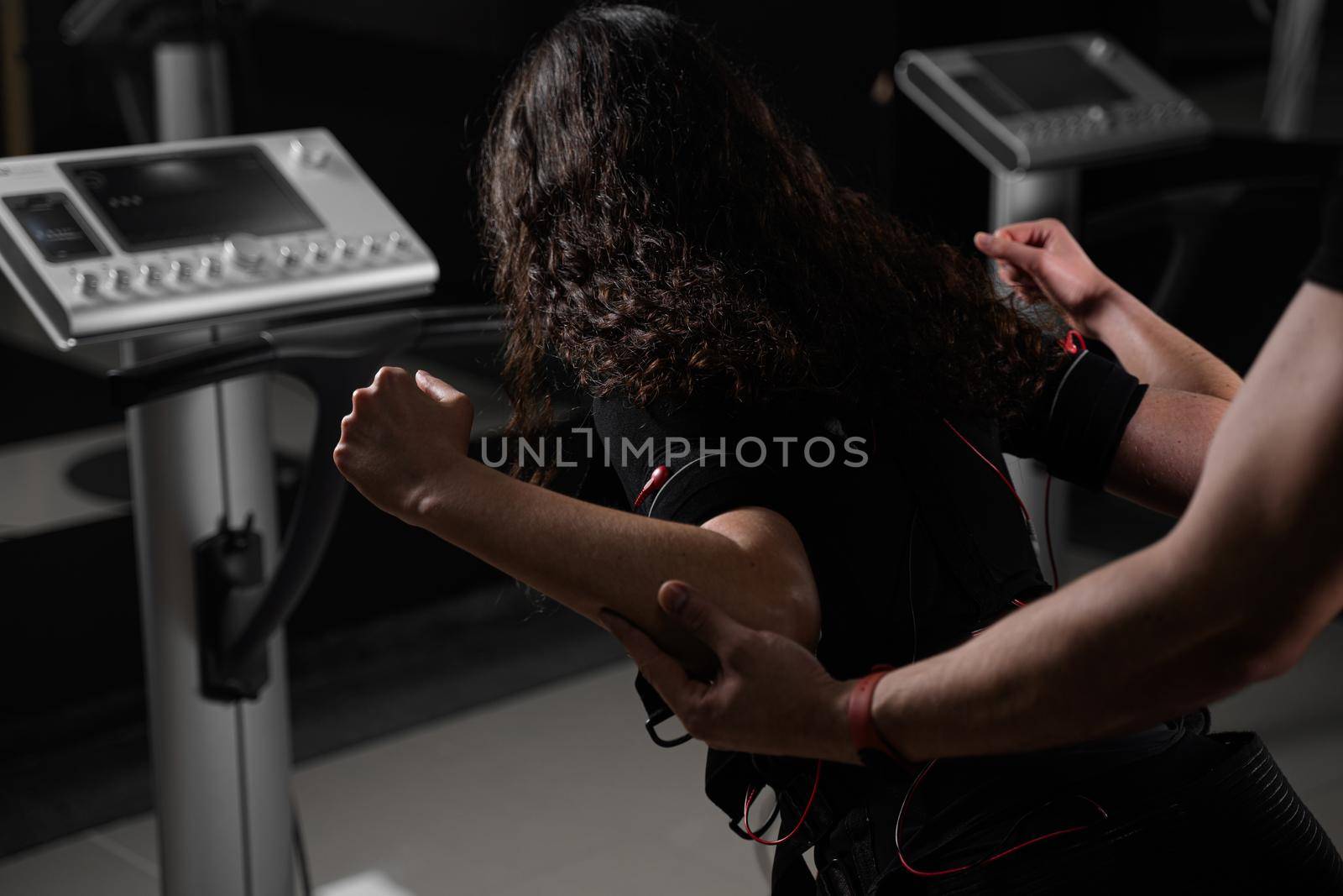 Making physical exercises using EMS suit in gym. Sport training in electrical muscle stimulation suit