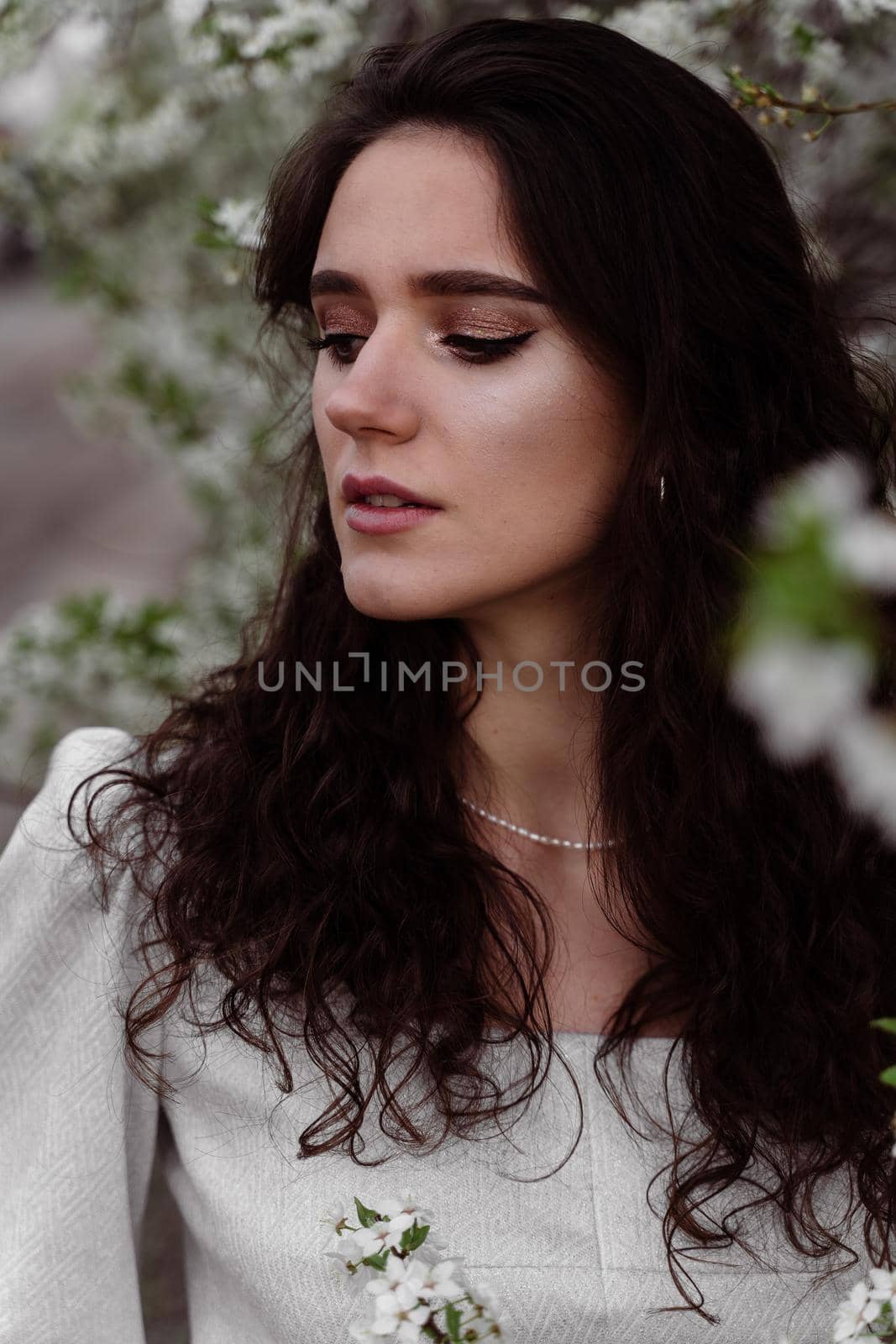 Lovely girl near blooming trees in the park. Outdoor walking in at sunny day. Lifestyle of young woman