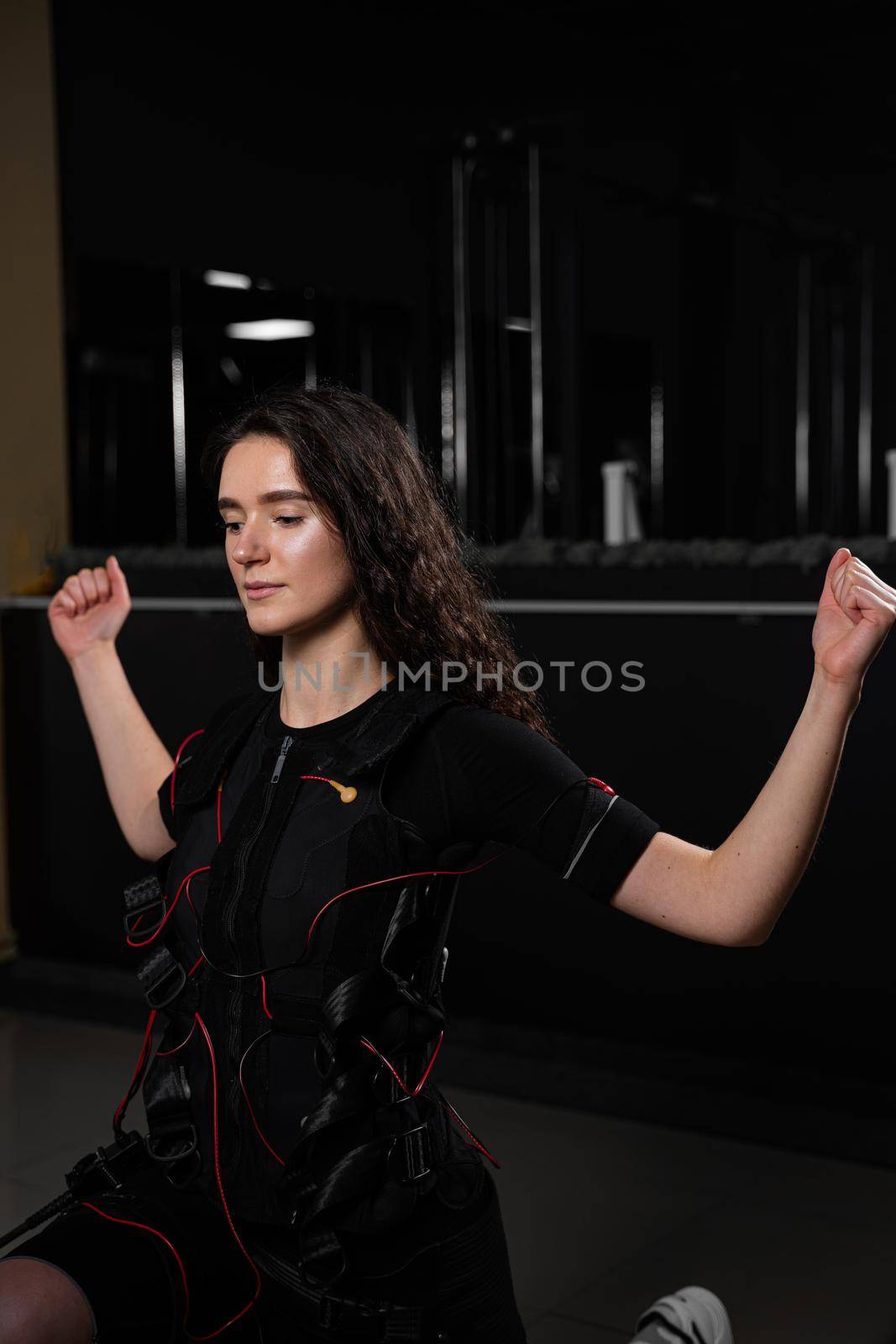 Girl in EMS suit in gym. Sport training in electrical muscle stimulation suit. by Rabizo