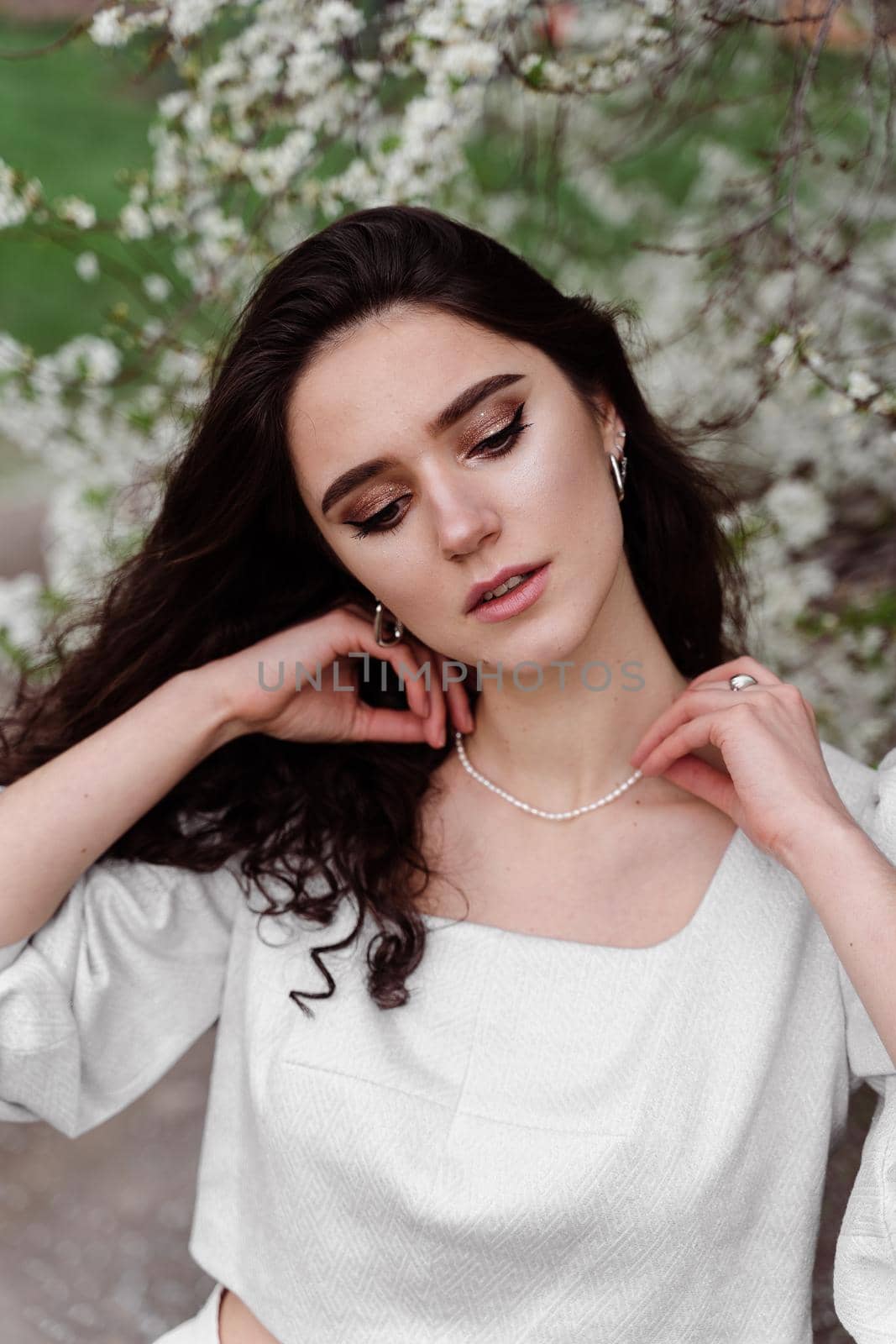 Spring lifestyle. Model posing near white blooming trees without mask outdoor countryside. Dreaming girl with curly hair. by Rabizo