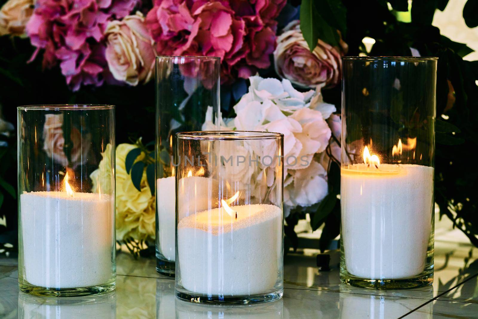 Burning candles on the background of different flowers by jovani68