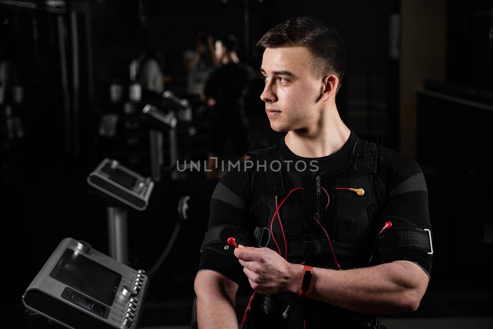 Man with electronic contactor of EMS suit in gym. Sport training in electrical muscle stimulation suit