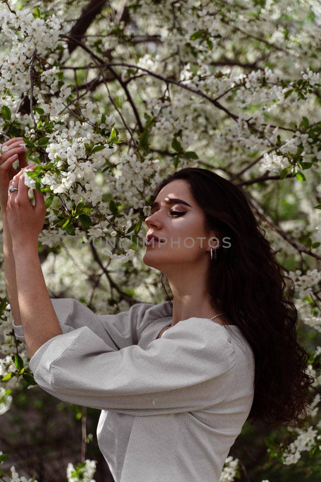 Lovely girl near blooming trees in the park. Outdoor walking in at sunny day. Lifestyle of young woman. by Rabizo