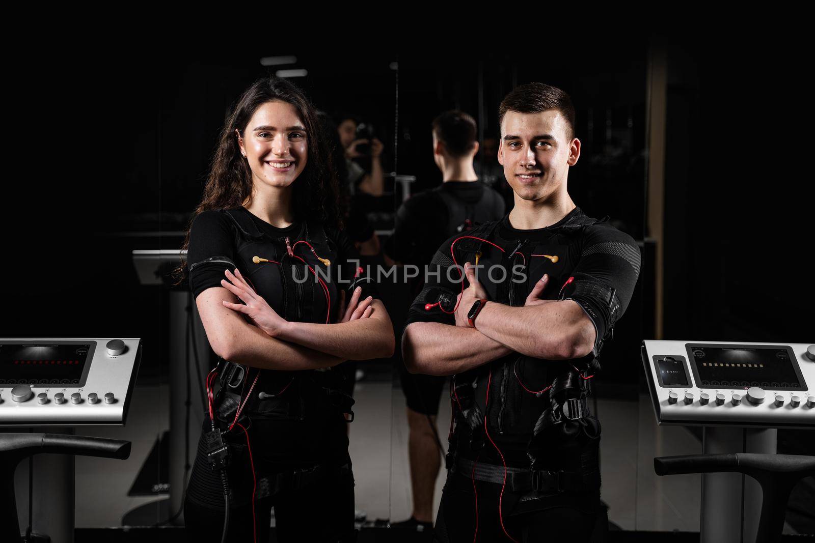 man and a woman in an EMS vest are standing side by side and smiling. 2 trainers in gym. by Rabizo