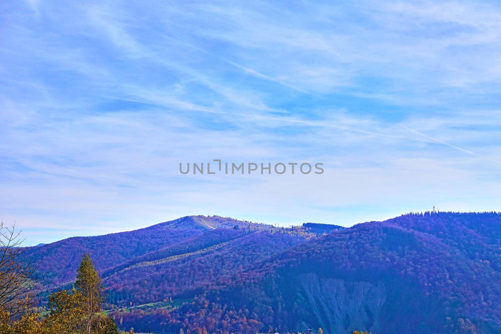 a large natural elevation of the earth's surface rising abruptly from the surrounding level, a large steep hill.Mountain range in autumn colors and blue sky.