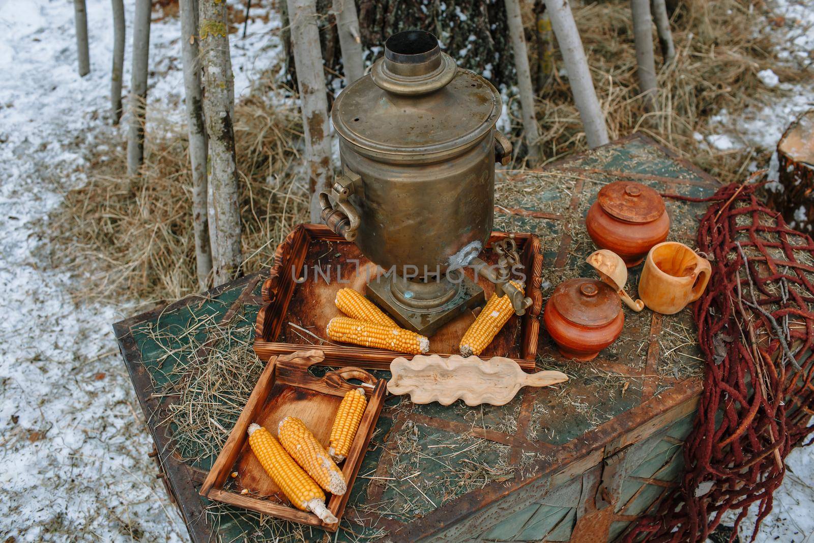 An old samovar standing on a chest in the winter forest.