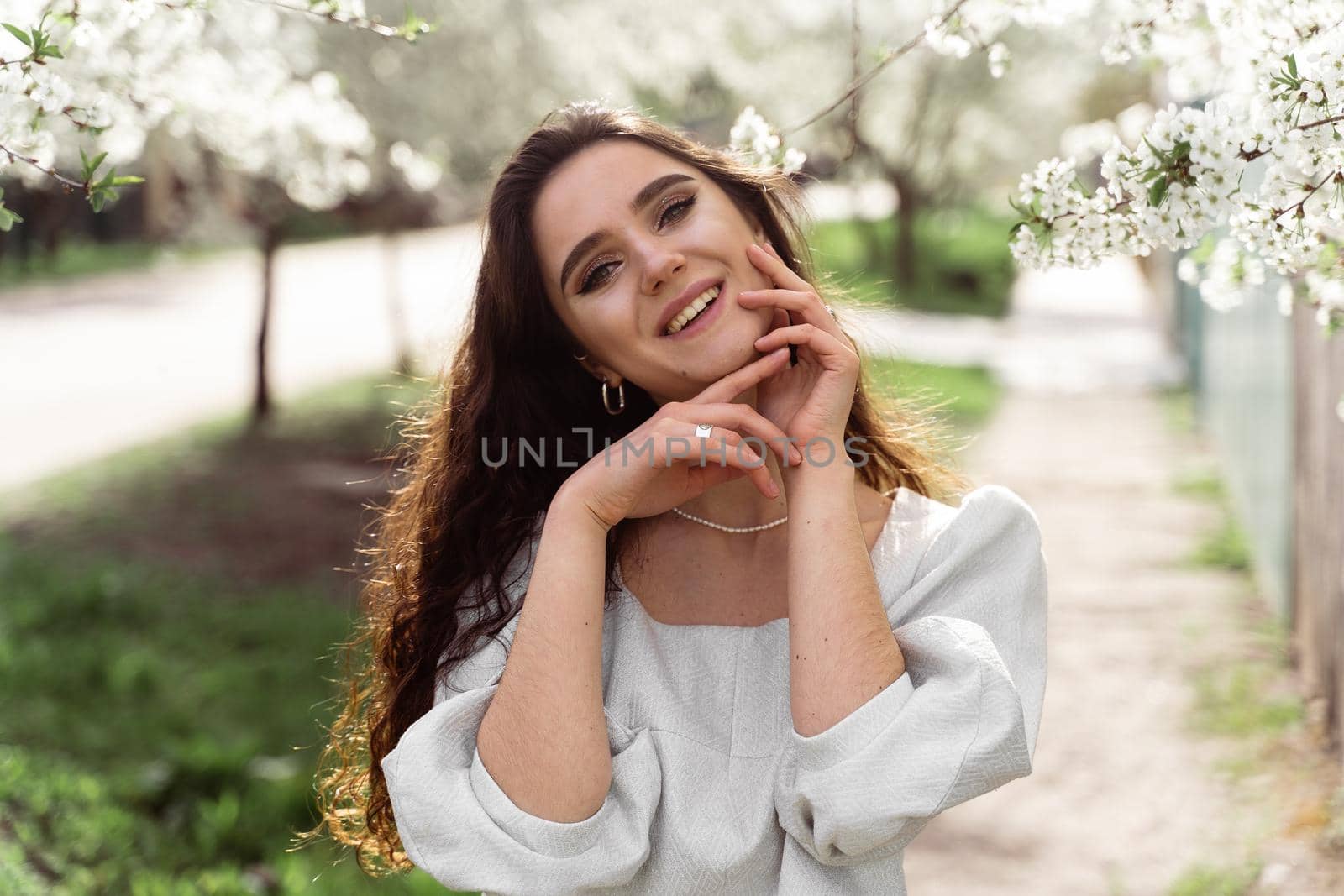 Lovely girl near blooming trees in the park. Outdoor walking in at sunny day. Lifestyle of young woman.