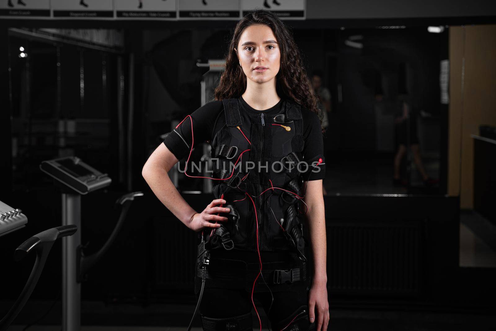 Girl in EMS suit in gym. Sport training in electrical muscle stimulation suit. by Rabizo