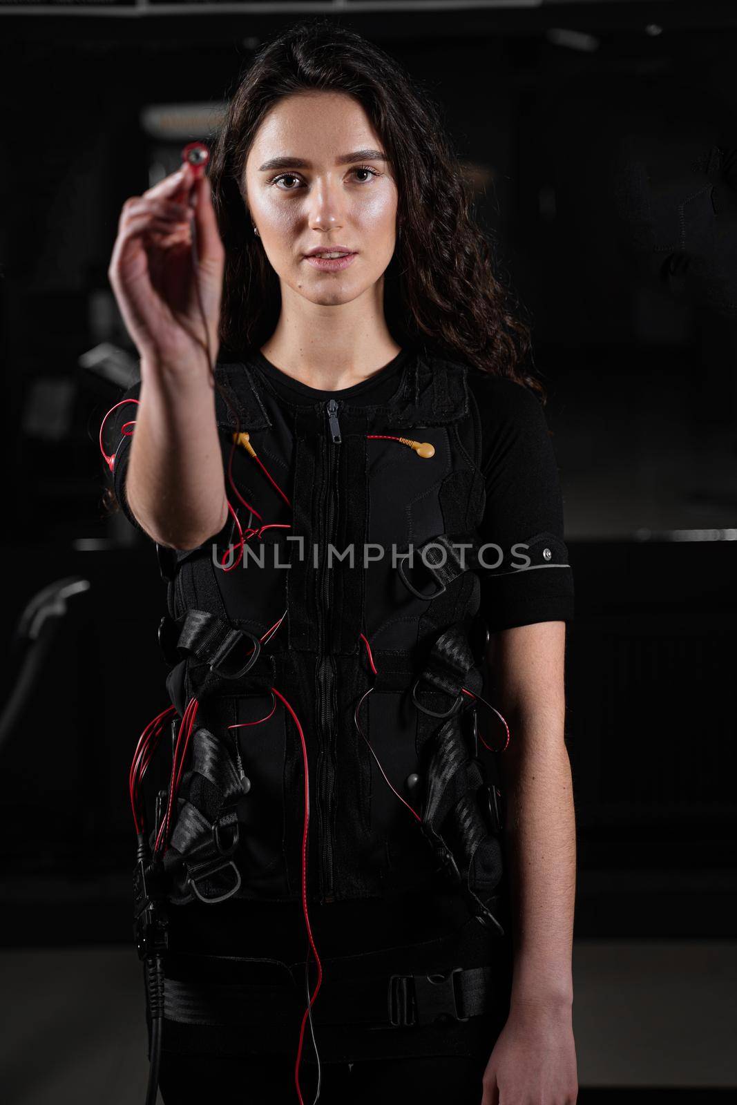 Girl with electronic contactor of EMS suit in gym. Sport training in electrical muscle stimulation suit