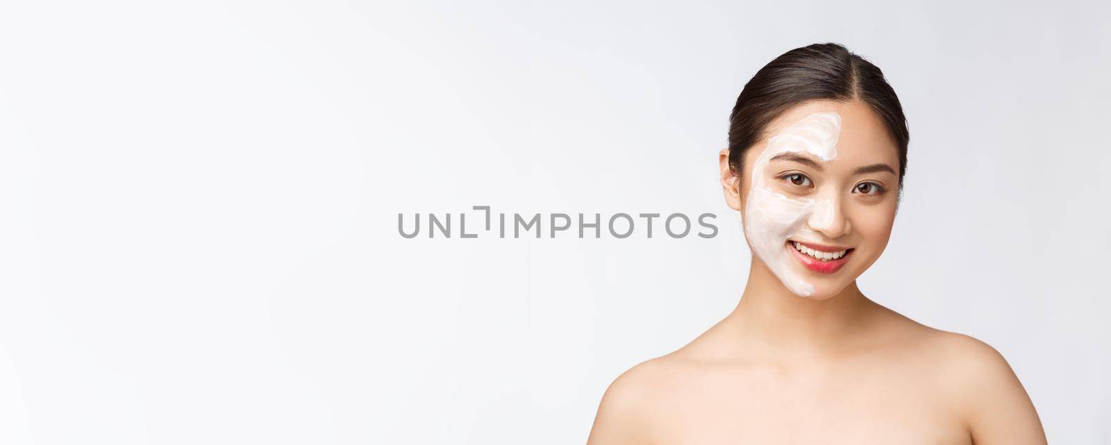 Charming pleasant woman applying cream on half face.
