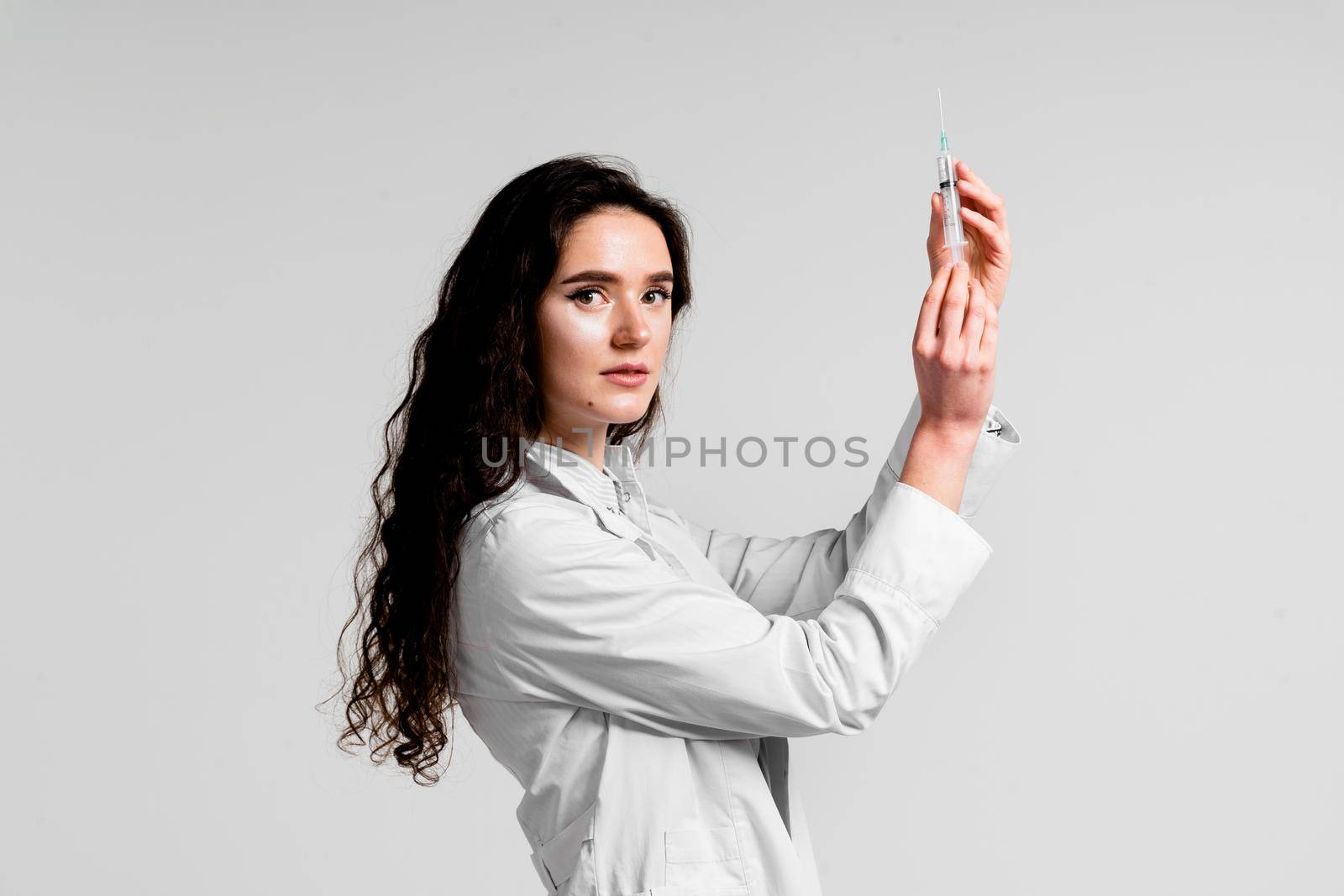 Doctor holding syringe with coronavirus vaccine. Covid-19 Vaccination. Stop quarantine. Attractive girl in medical gloves with syringe and medication. by Rabizo